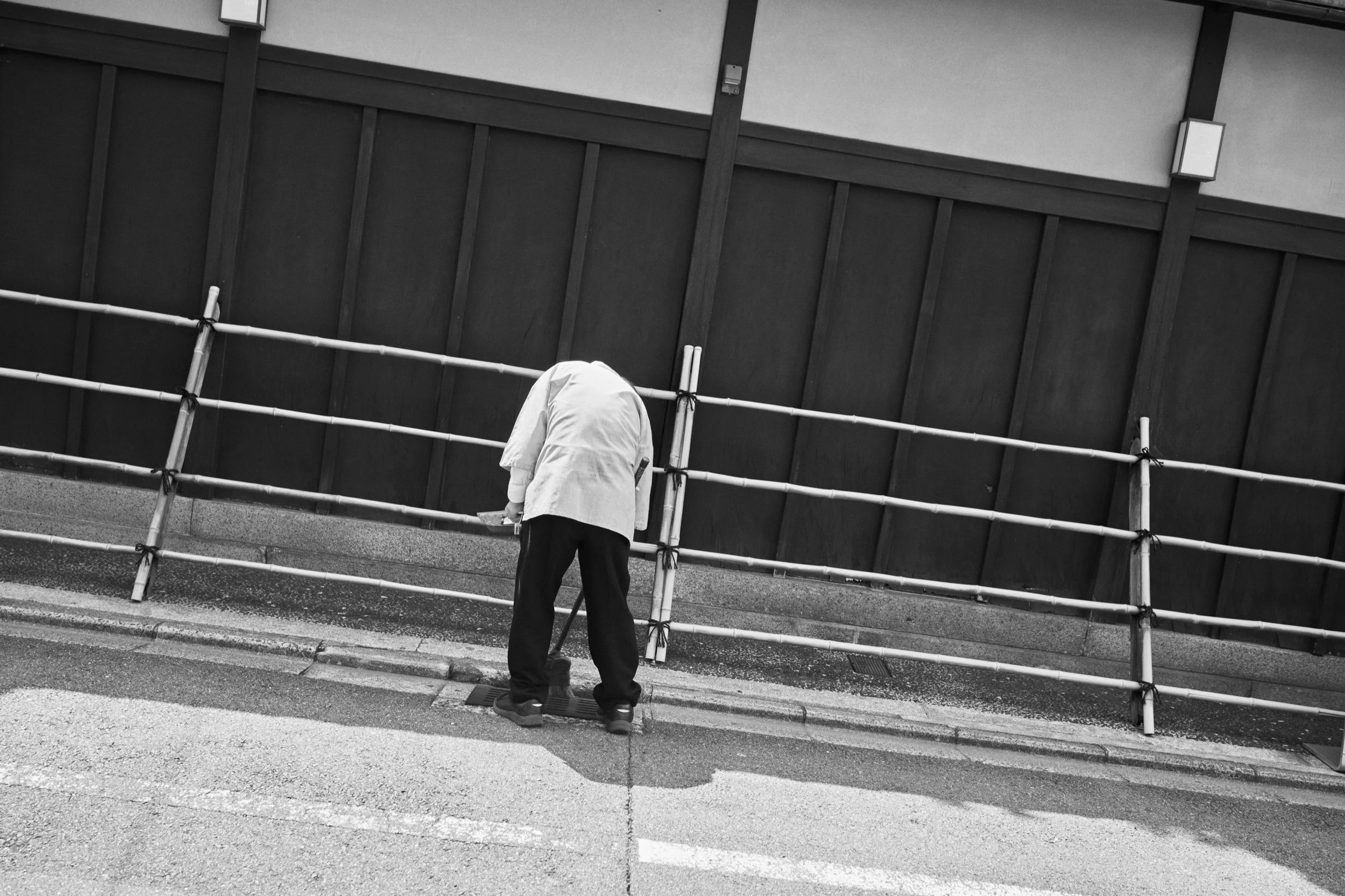 A street worker sweeps the pavement. Kyoto.