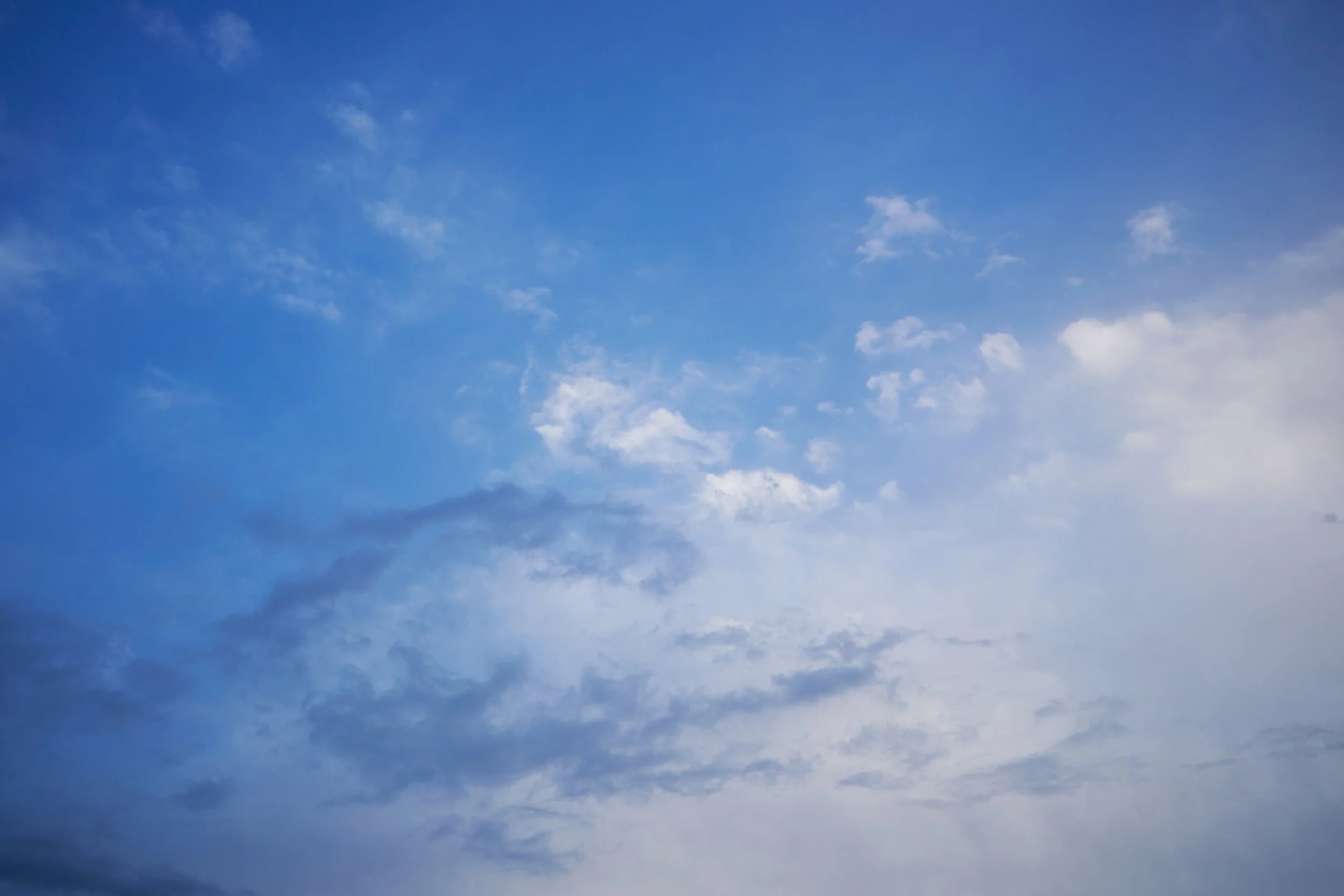 Scattered white and grey clouds against a deep blue sky.