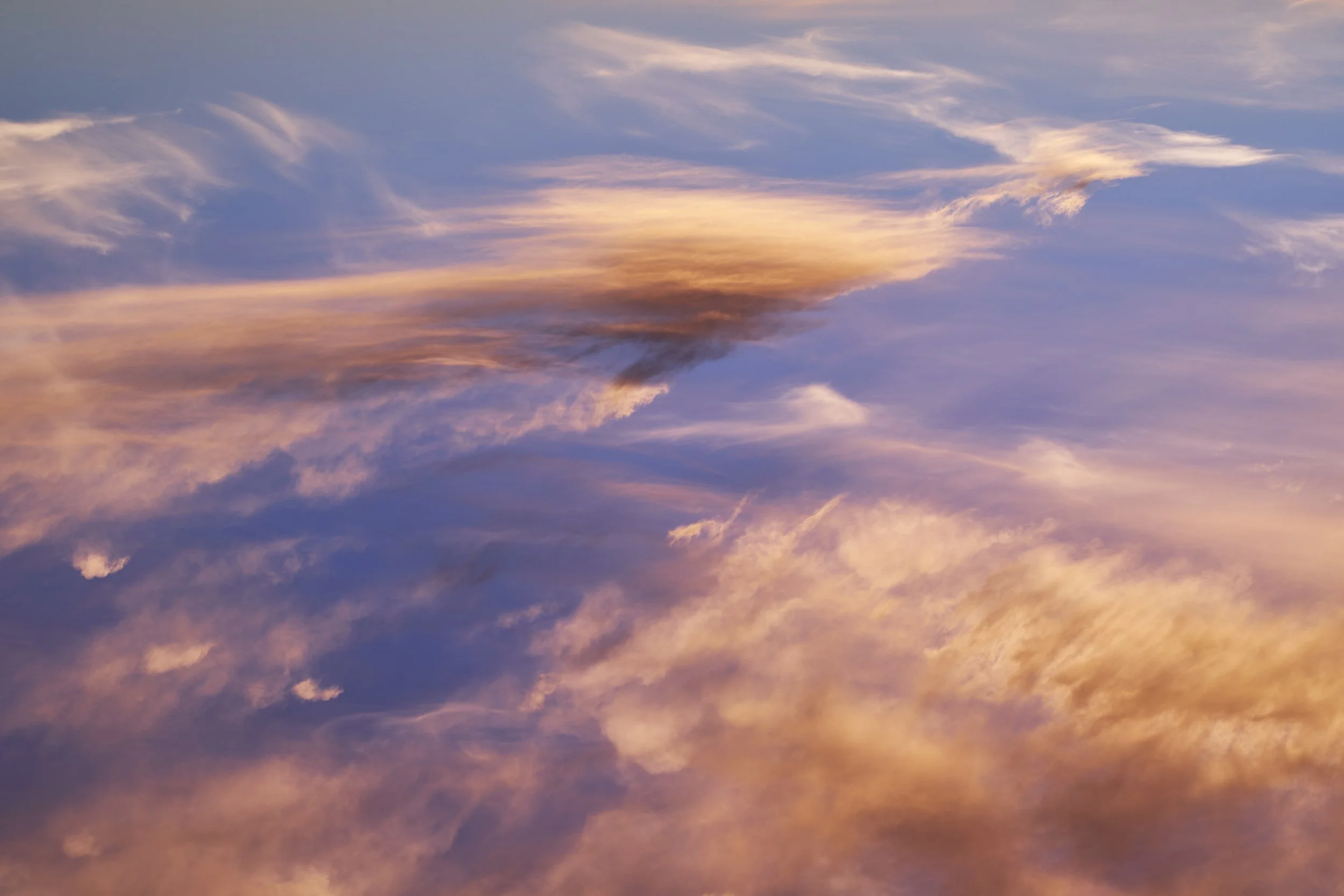 Sweeping golden clouds and darker cloud bands against a purple-blue sky.