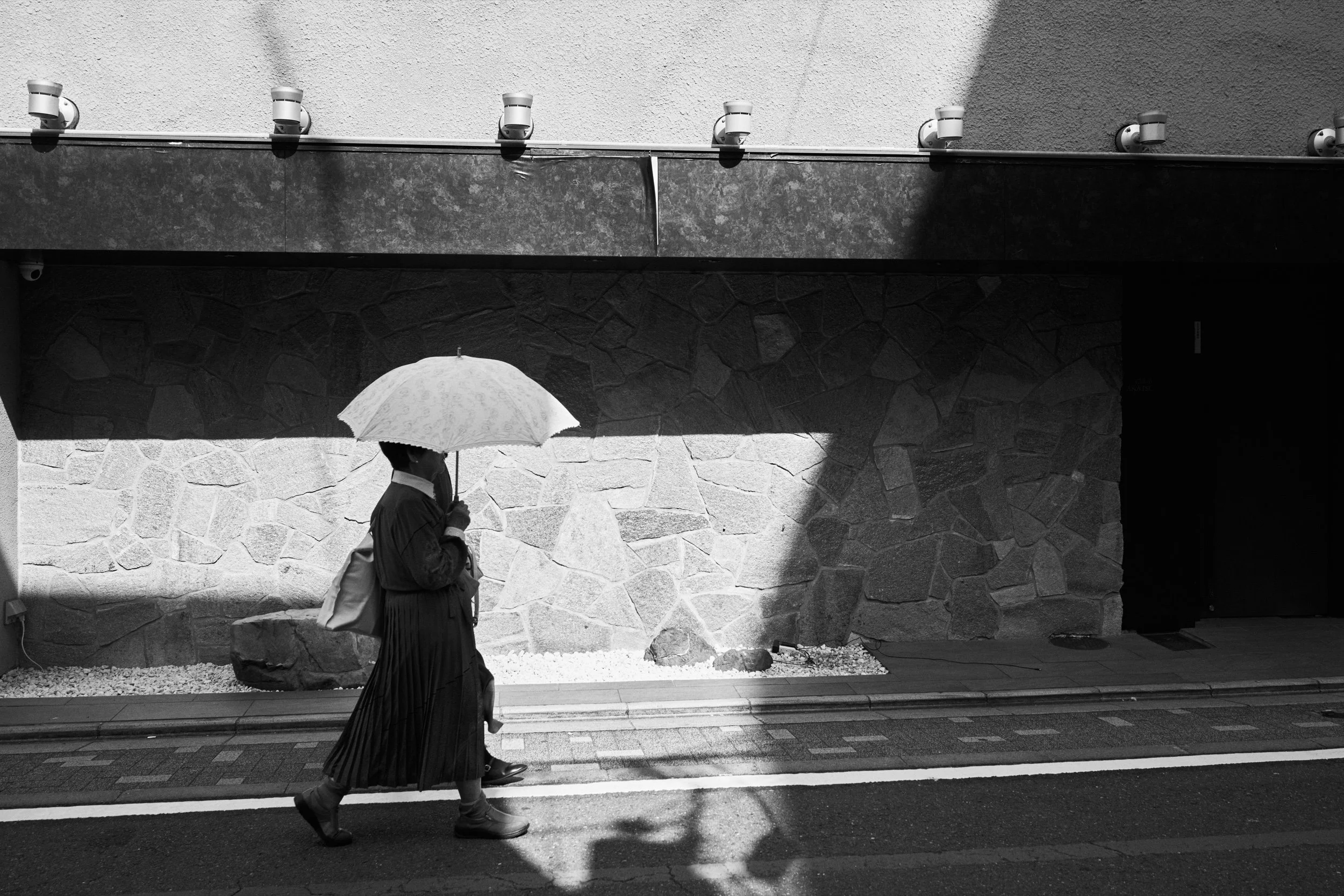 A pedestrian carrying an umbrella. Kyoto.