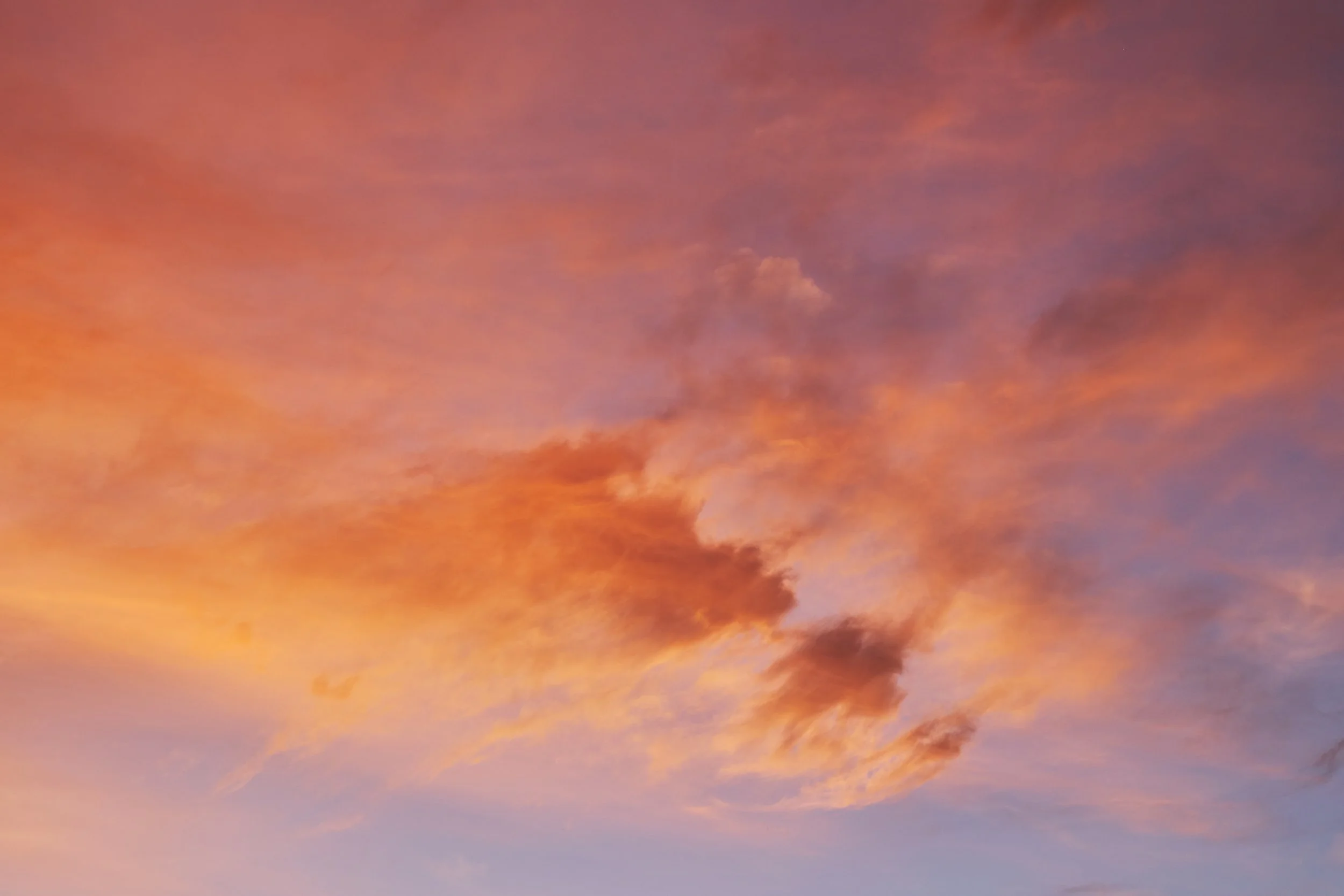 Orange and pink clouds glowing against a purple sky.