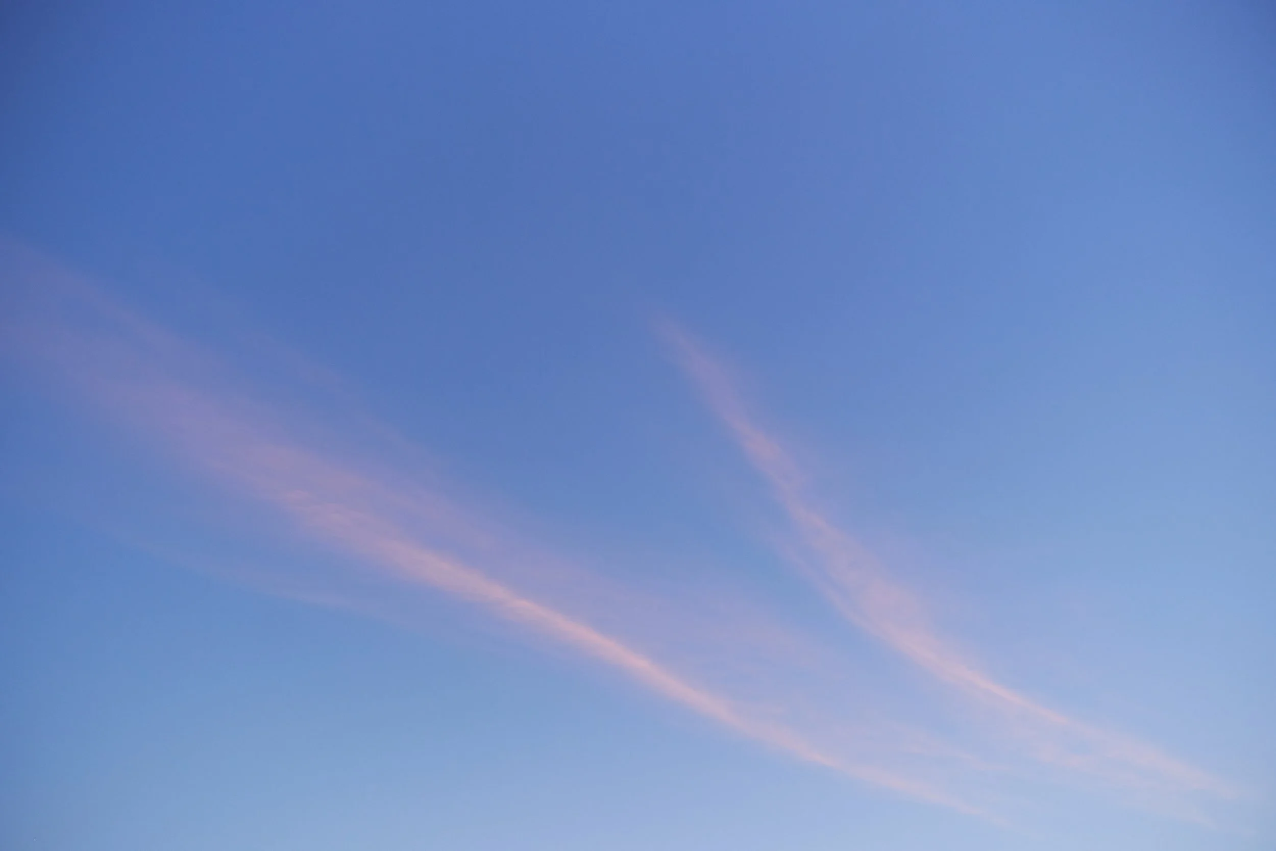 Fine pink cloud streaks across a pale blue sky.