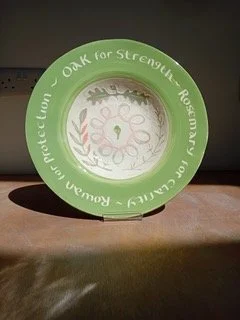 Green round ornament with white center, floral design, and text reading 'Proud to Protect Our Own, Oak for Strength...' on a wooden surface.