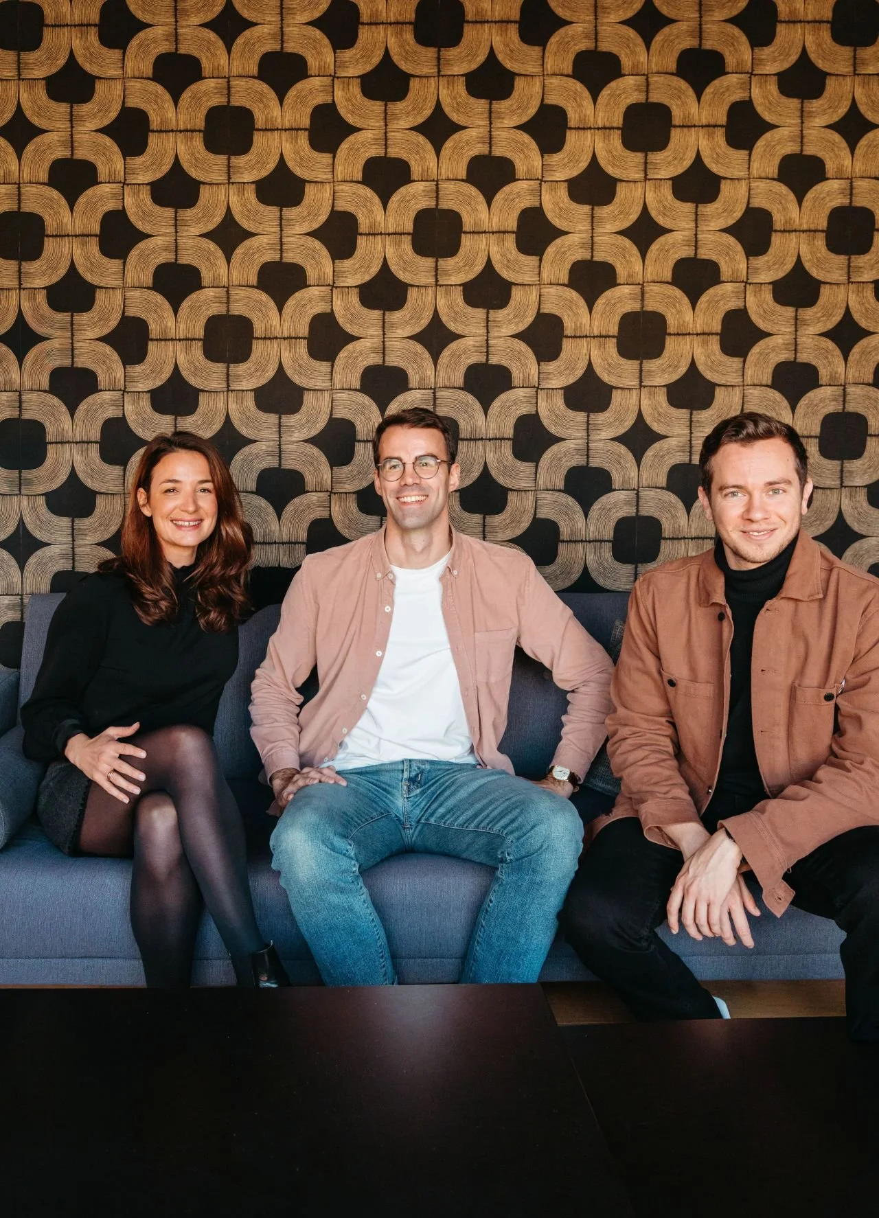 Photo des cofondateurs de SMALL et SMALL Bordeaux, Fanny, Adrien et Sacha assis sur un canapé bleu