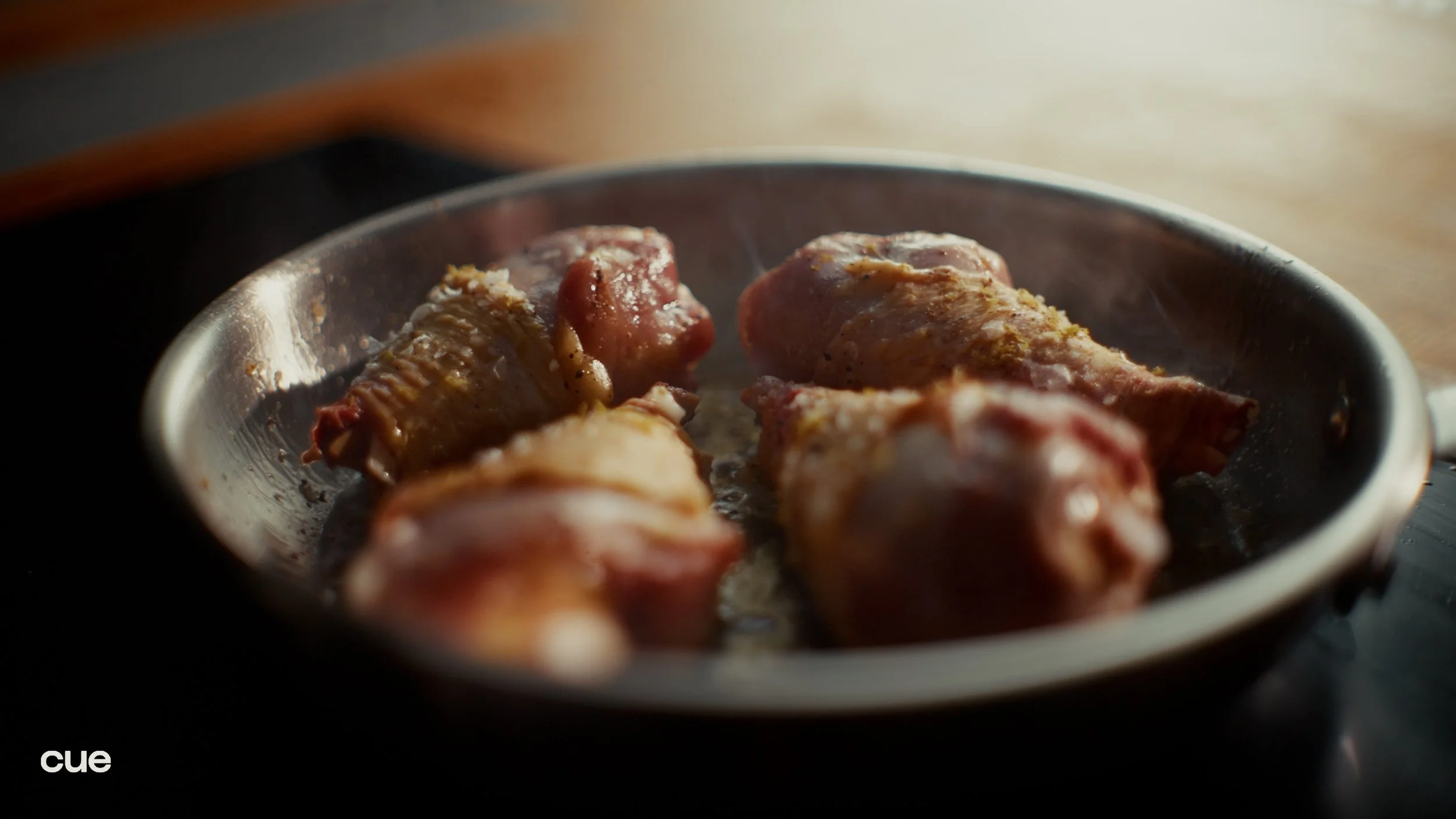 Raw chicken drumsticks in a skillet on a stove.