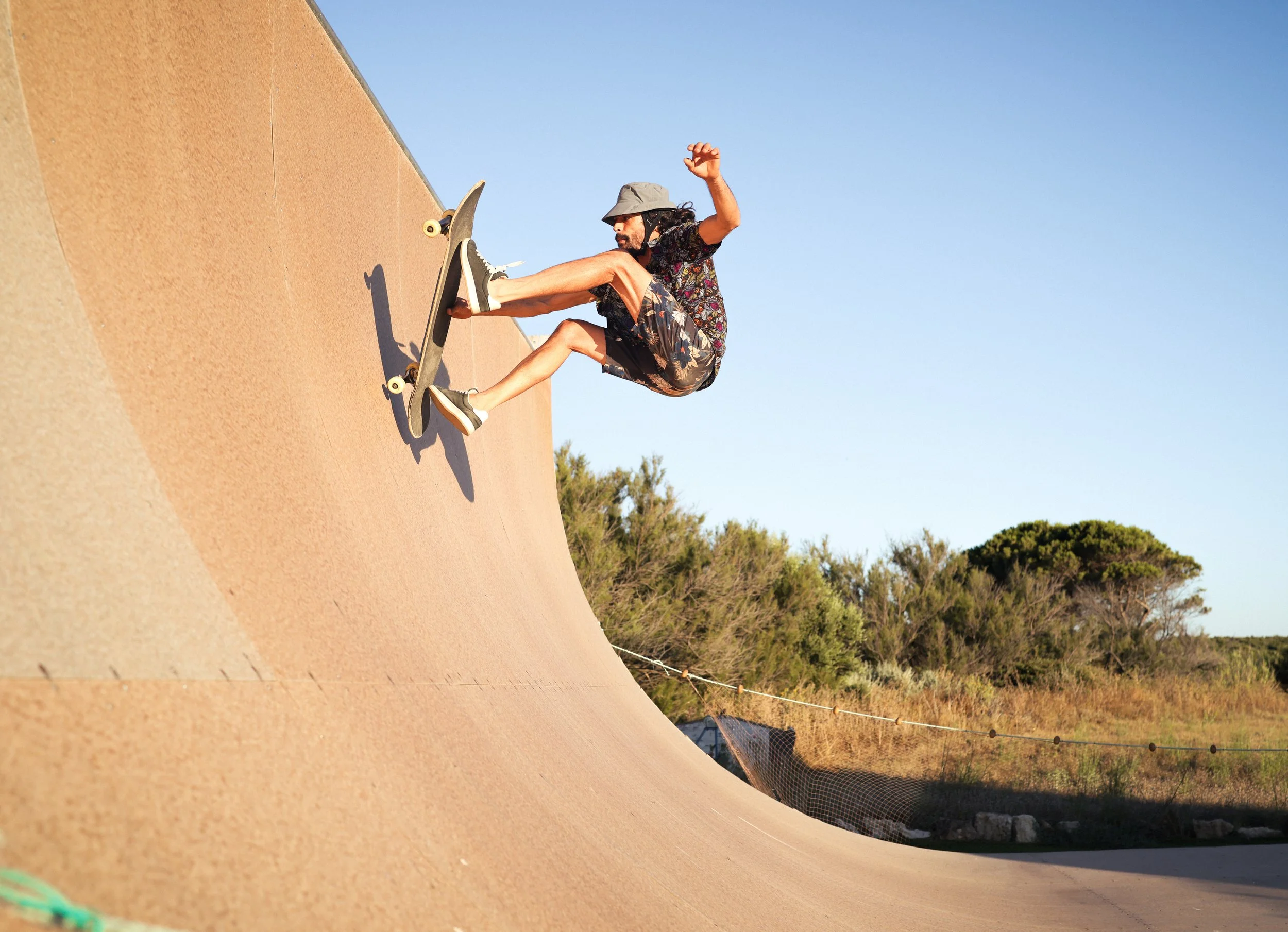Un chico esta haciendo un truco en la rampa con tabla de skate
