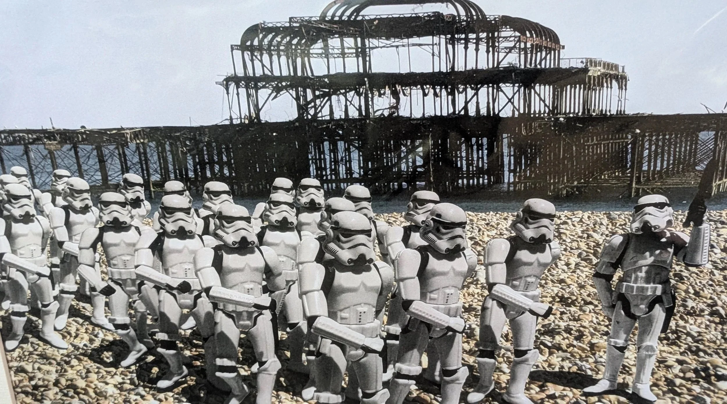 Star Wars stormtrooper toys arranged on Brighton beach in front of the west pier