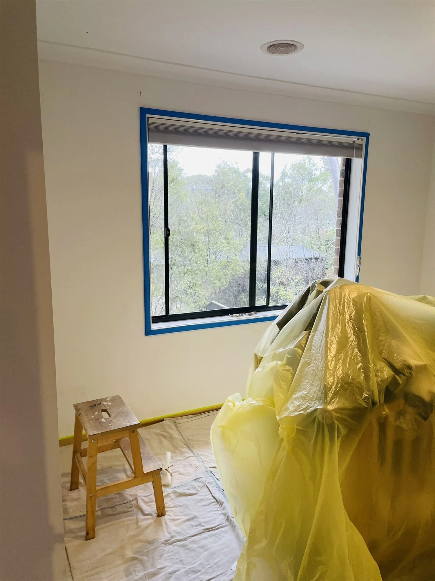 Nursery window masked and cot covered ahead of feature wall painting