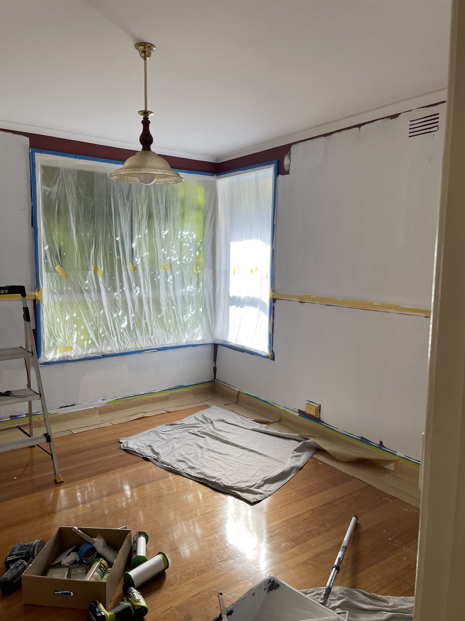 Bay window masked with plastic while walls are cut in during an interior repaint