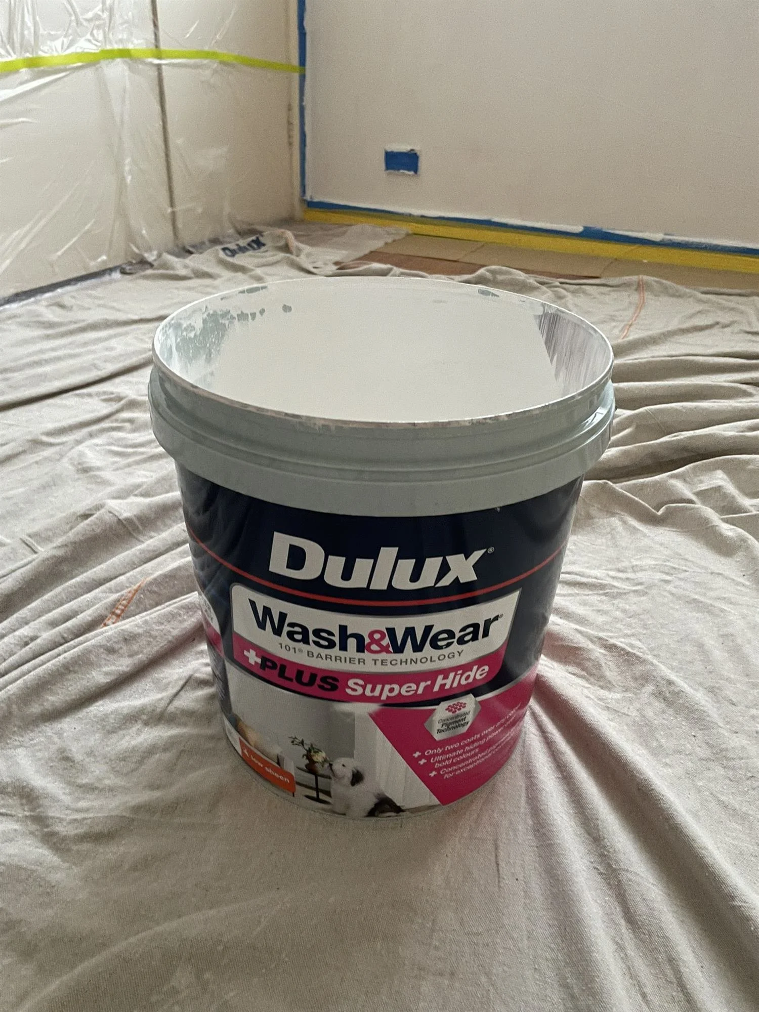 Tin of Dulux Wash and Wear paint on drop sheets during an interior repaint