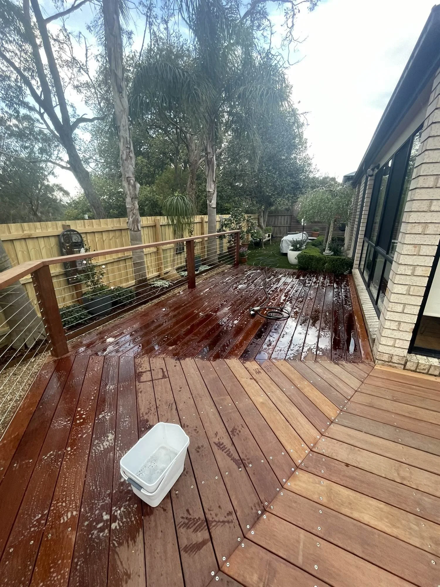 Deck oil going on to new hardwood boards, with wet and dry sections visible