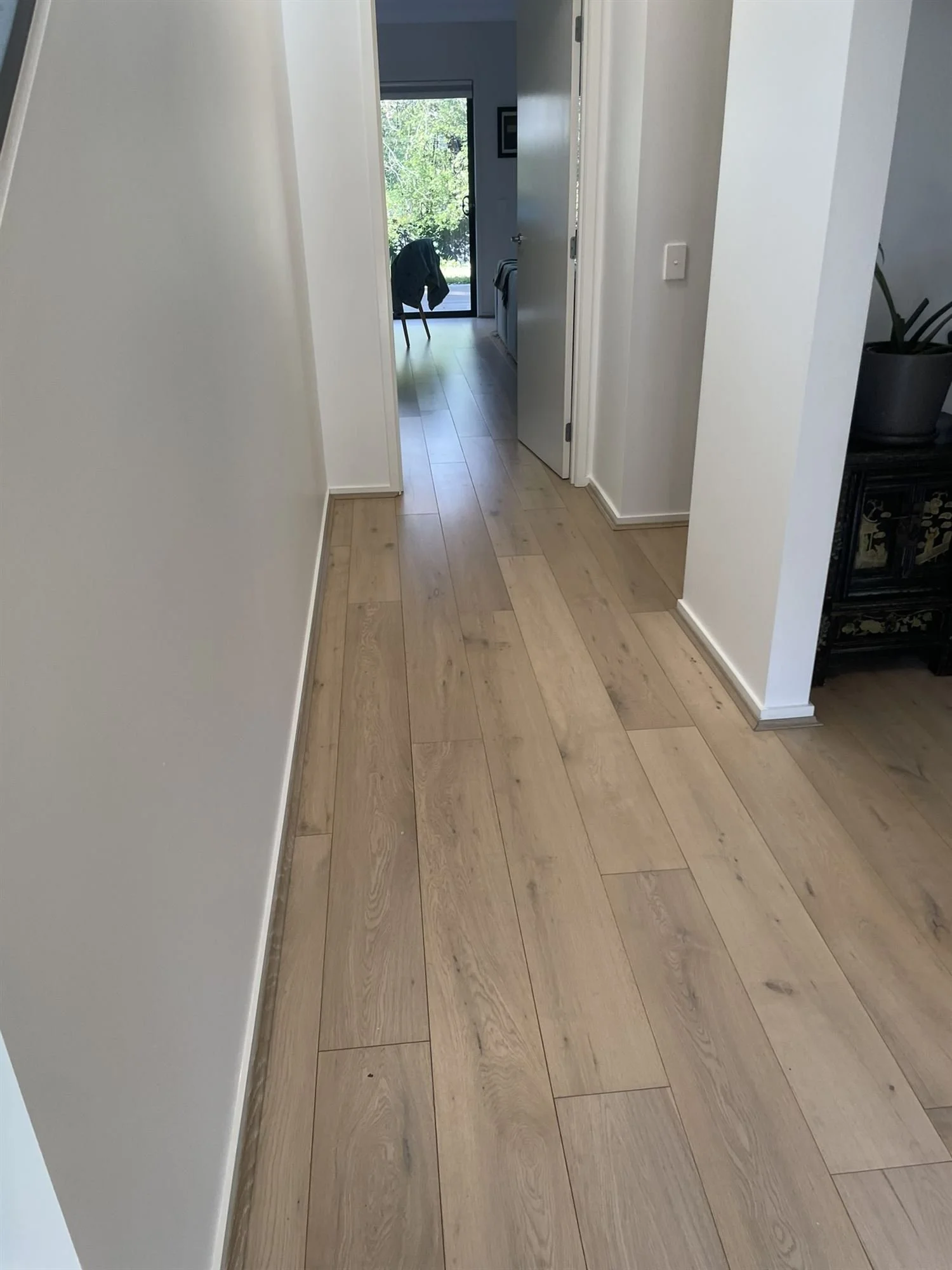 Freshly painted white hallway walls with a timber floor