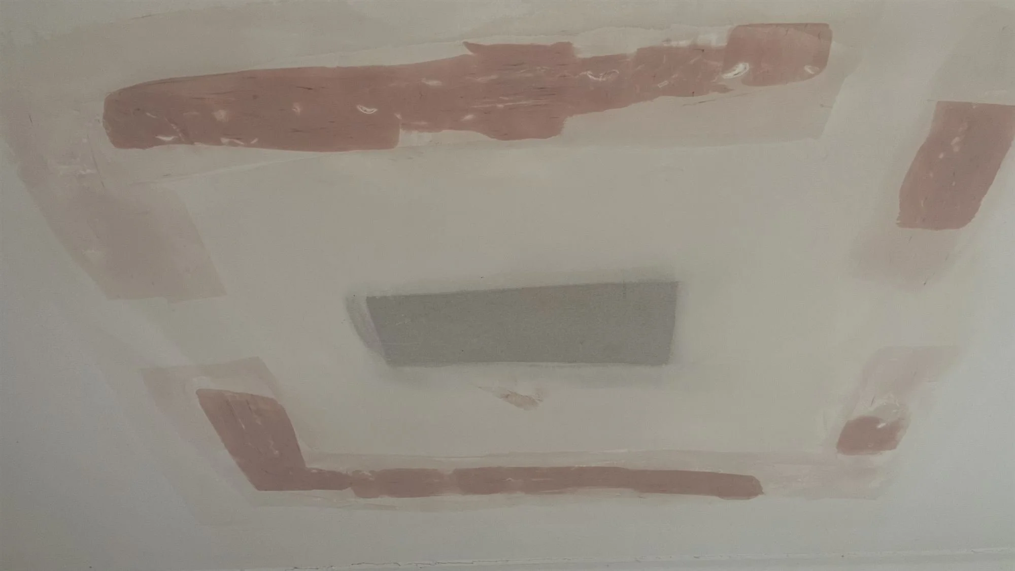 Repaired ceiling patches around an exhaust vent before painting