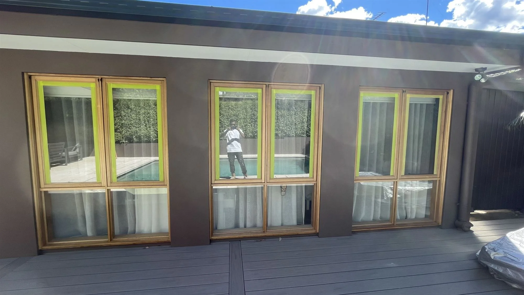 Timber windows and French doors masked with tape ready for clear coating