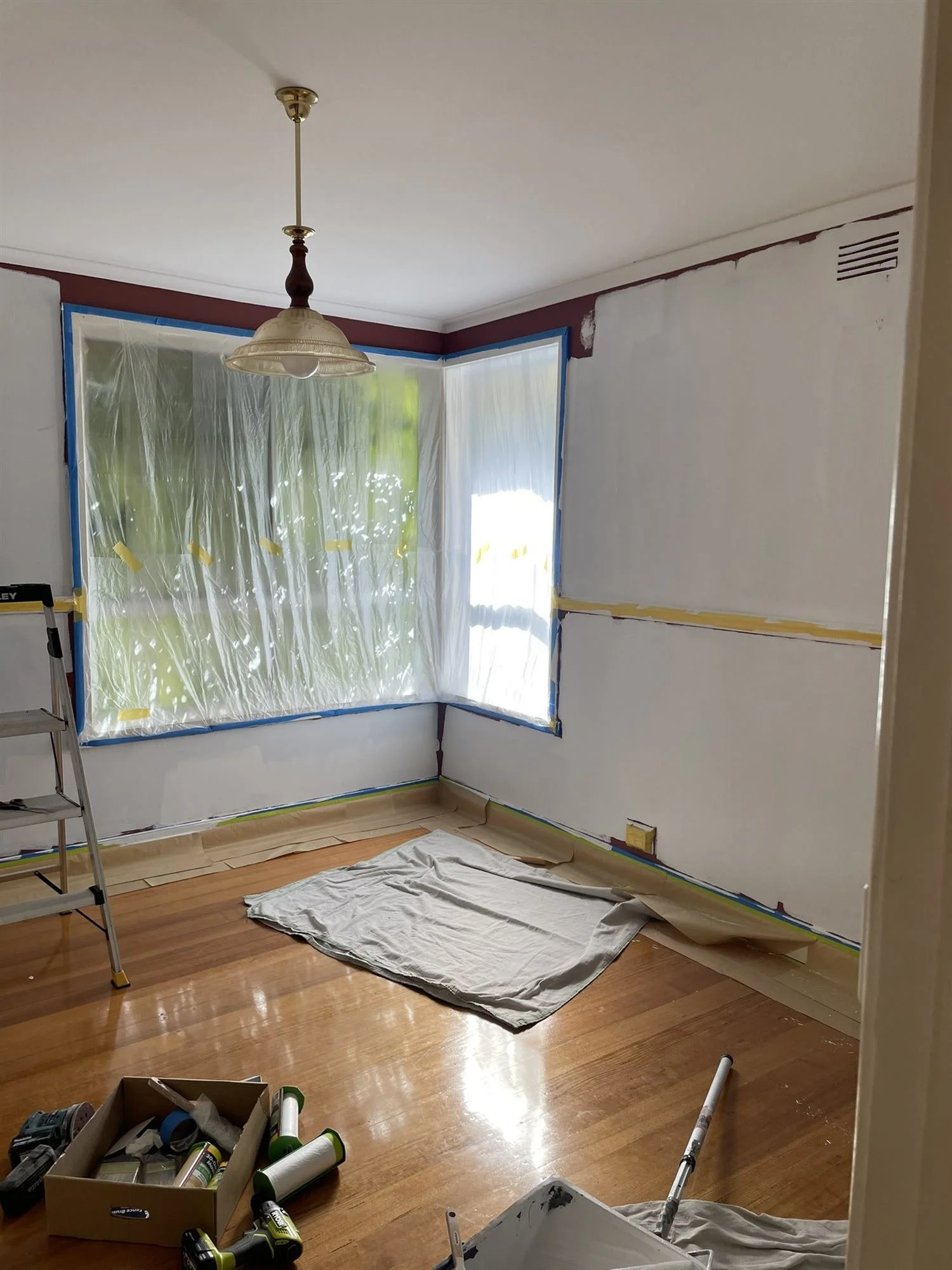 Room prepared for painting with the windows masked and the floor covered