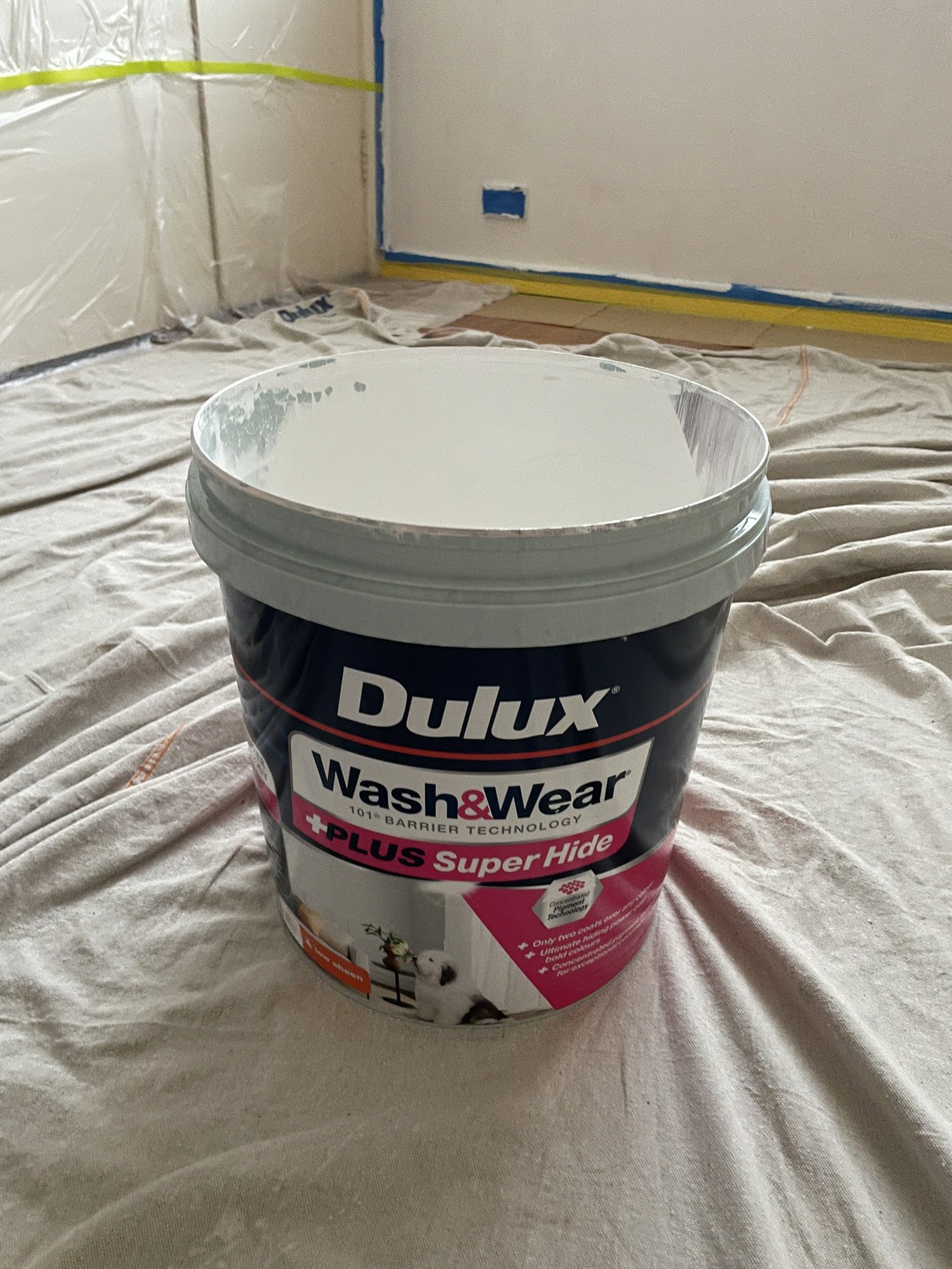 Tin of Dulux Wash&Wear paint on drop sheets during an interior repaint