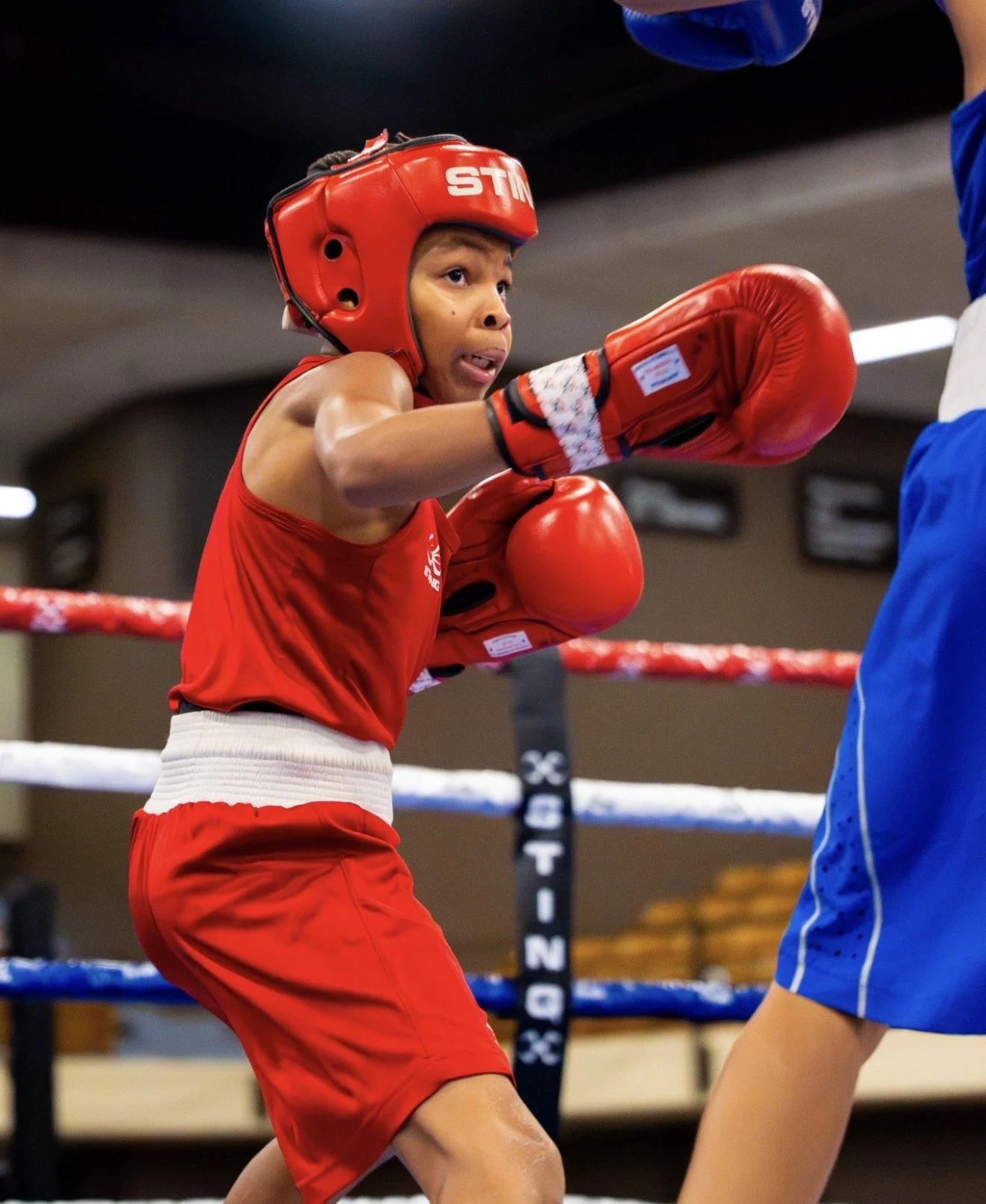 Levi Brown throws a punch in the boxing ring, wearing protective gear and displaying intense focus during his match.