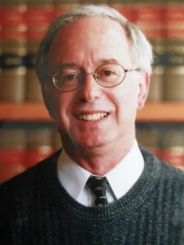 Smiling Harold B. Garwin, Esq., Board Vice-Chairperson, with glasses and books in the background