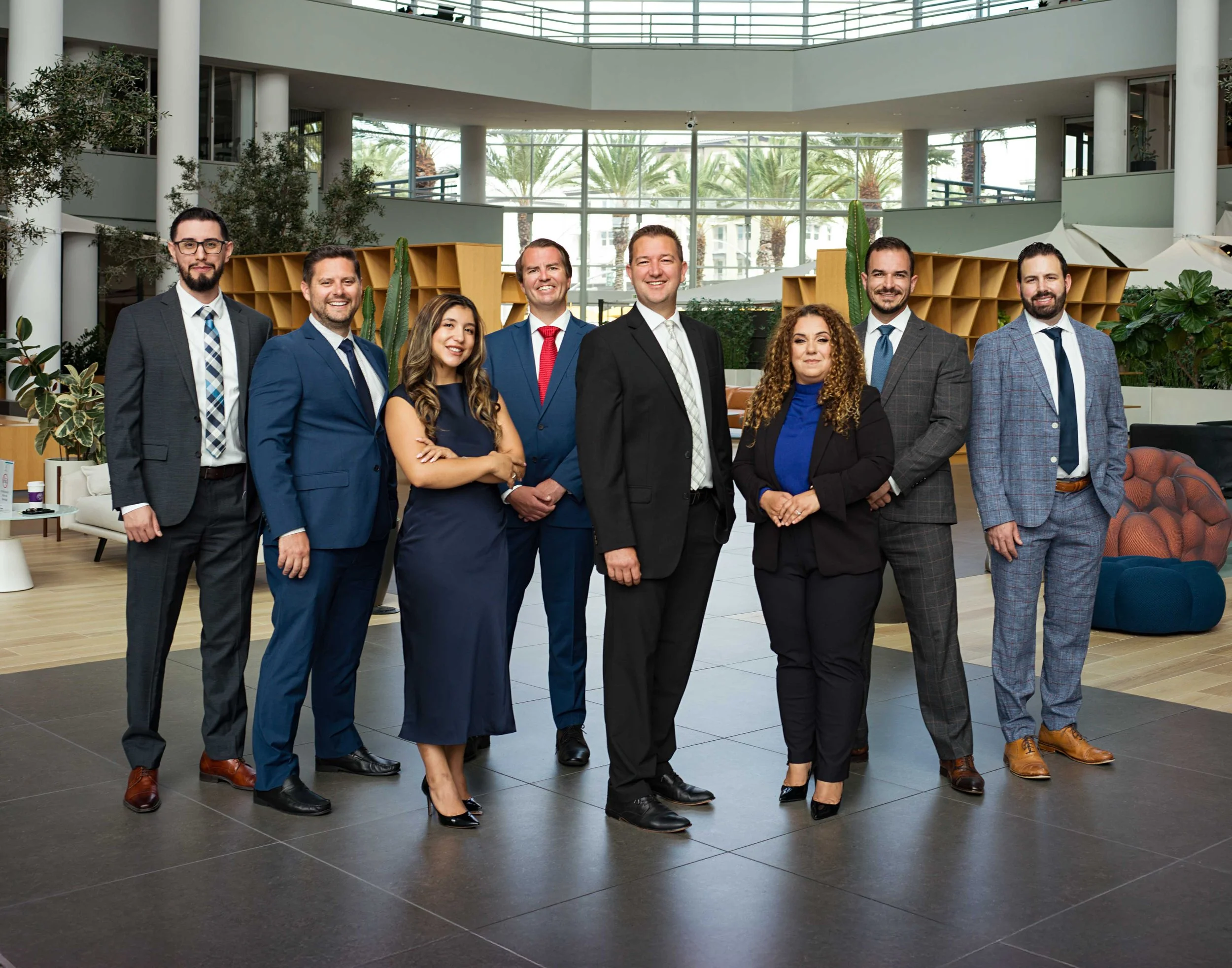 A polished environmental business portrait by Domain Photography, capturing a dynamic group of financial experts in a modern architectural setting. The team stands confidently in a contemporary office environment with floor-to-ceiling windows, natura