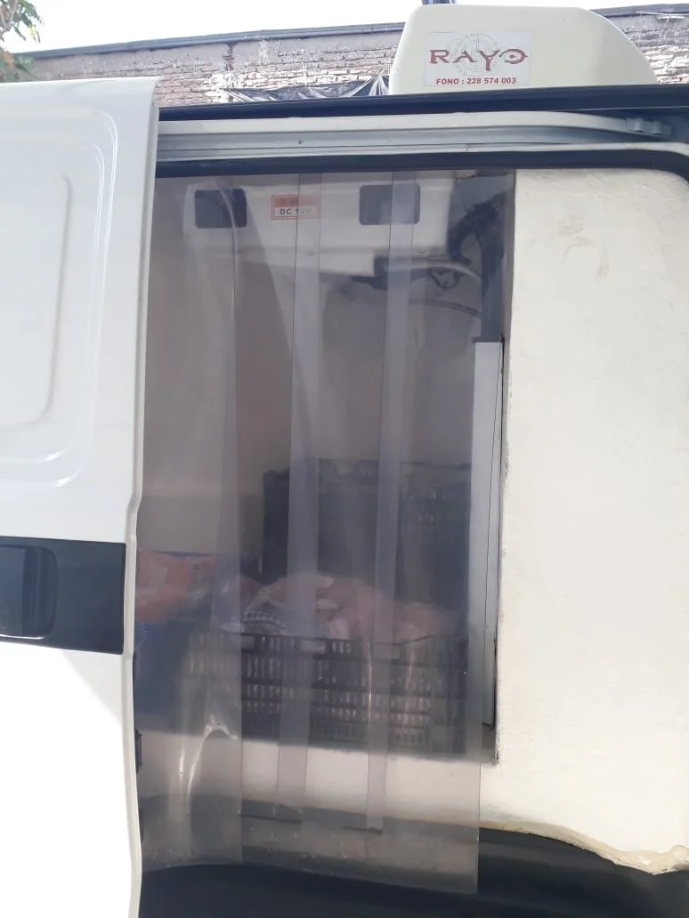 Puerta de un vehículo, posiblemente de reparto o de ventas, con una cortina de plástico transparente