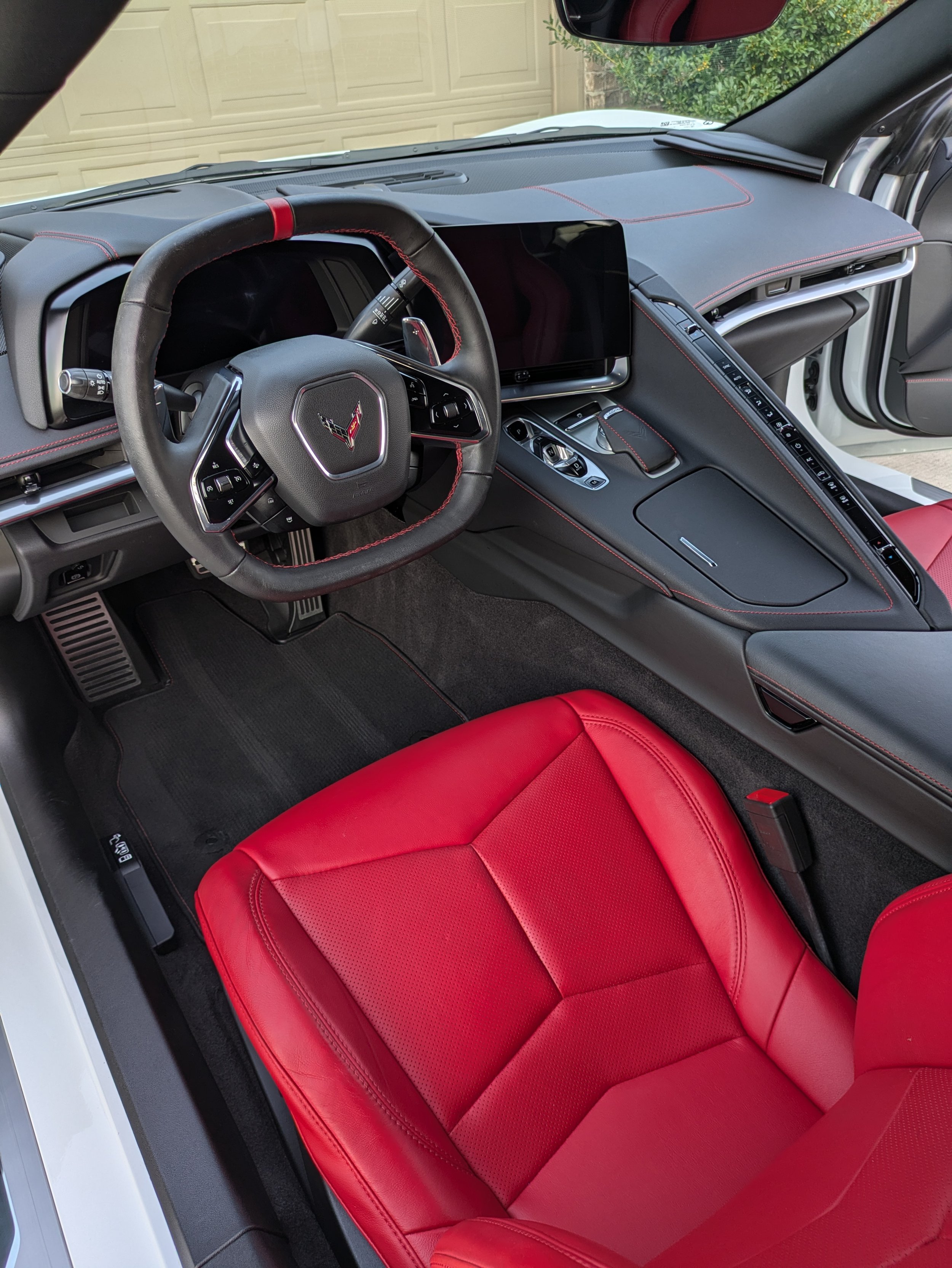 Interior of a sports car with red leather seats, a black steering wheel, and a digital dashboard.