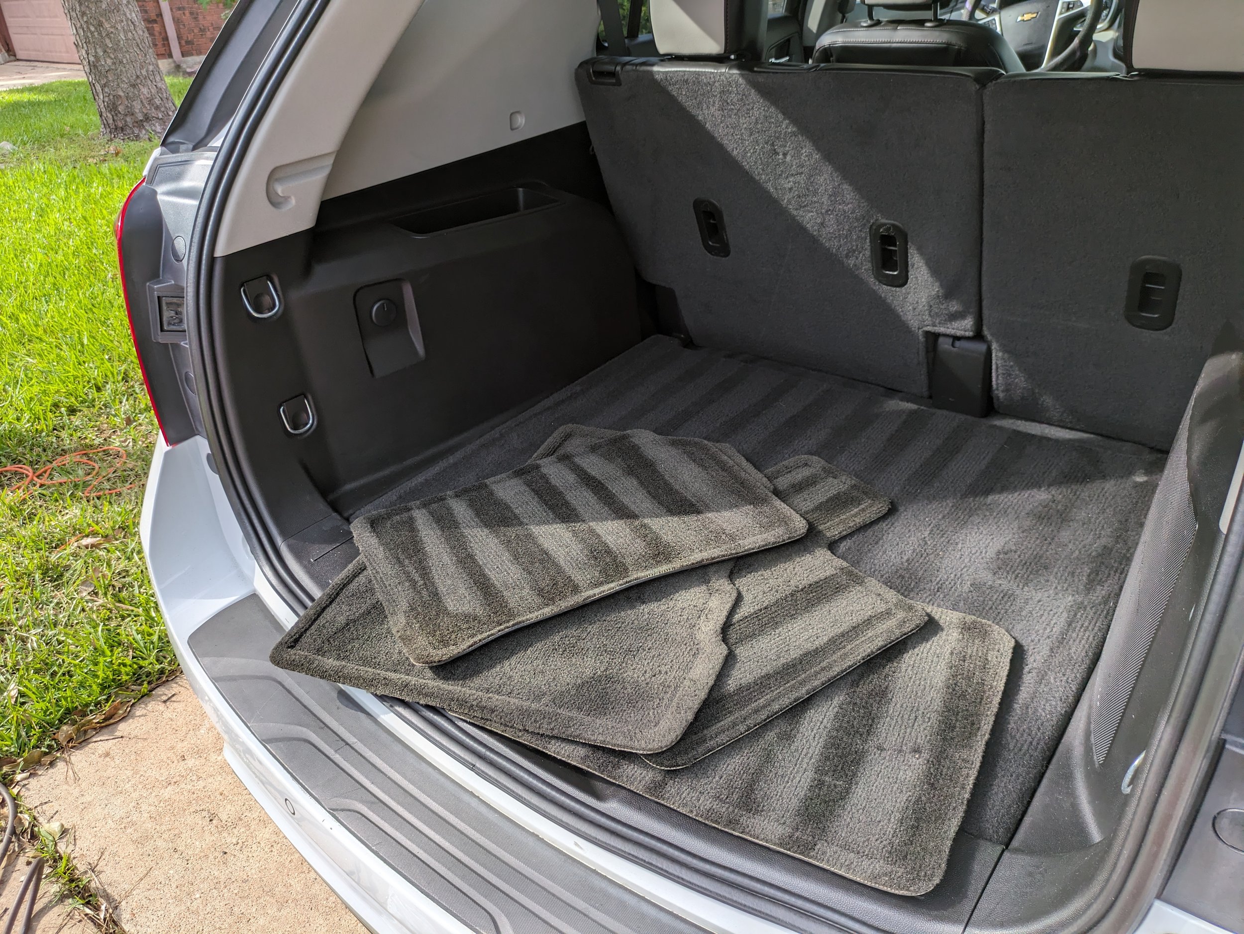 Open trunk of a vehicle with black floor mats on the carpeted interior.