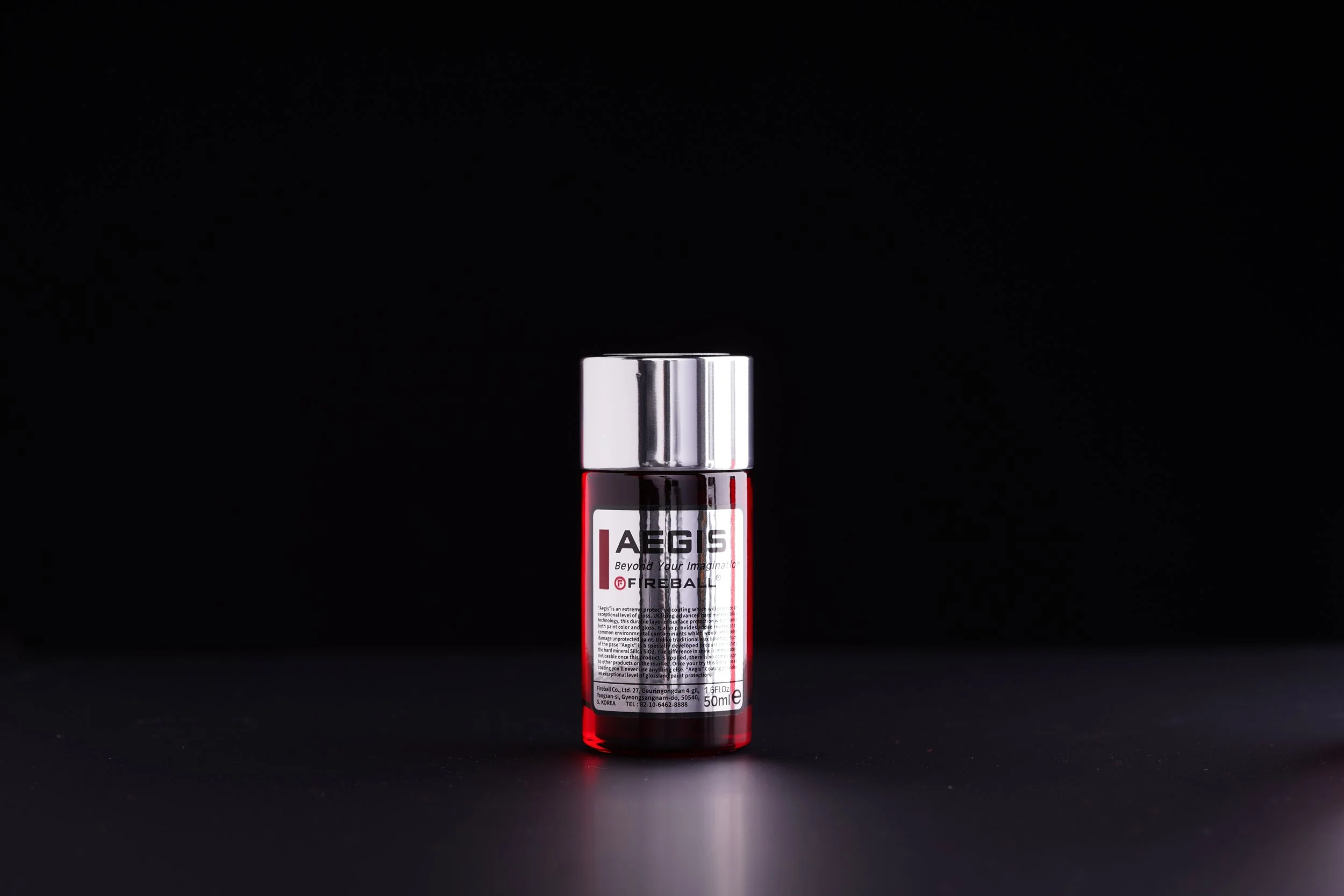 A cylindrical aerosol spray can with a metallic silver cap and a red and white body, displaying the brand name 'AEGIS' and product information, set against a black background.