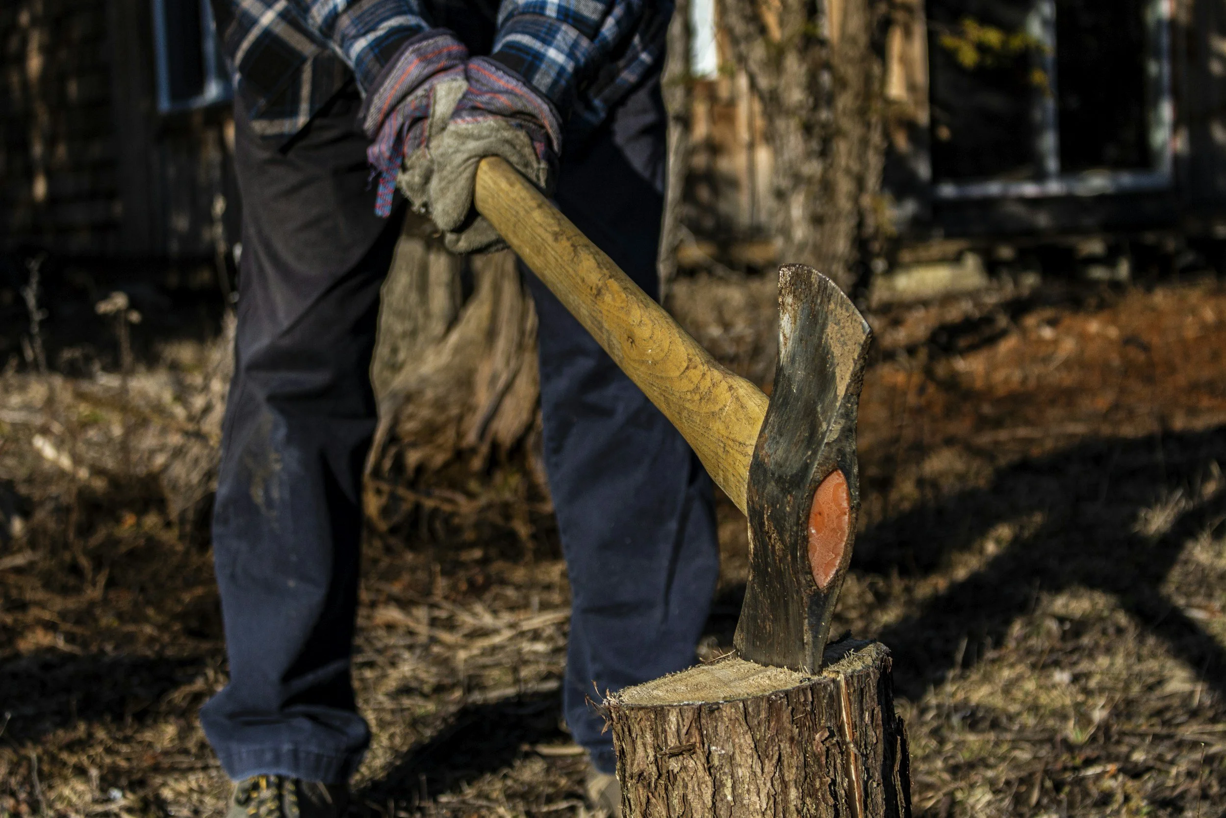 Person splitting a log with a sledgehammer outdoors.
