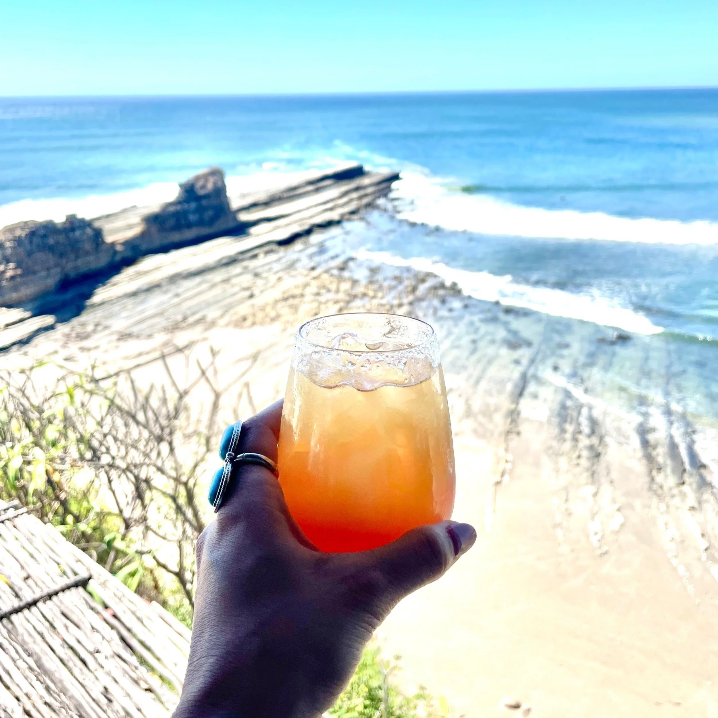A woman is holding an orange cocktail overlooking the Pacific Ocean in Nicaragua
