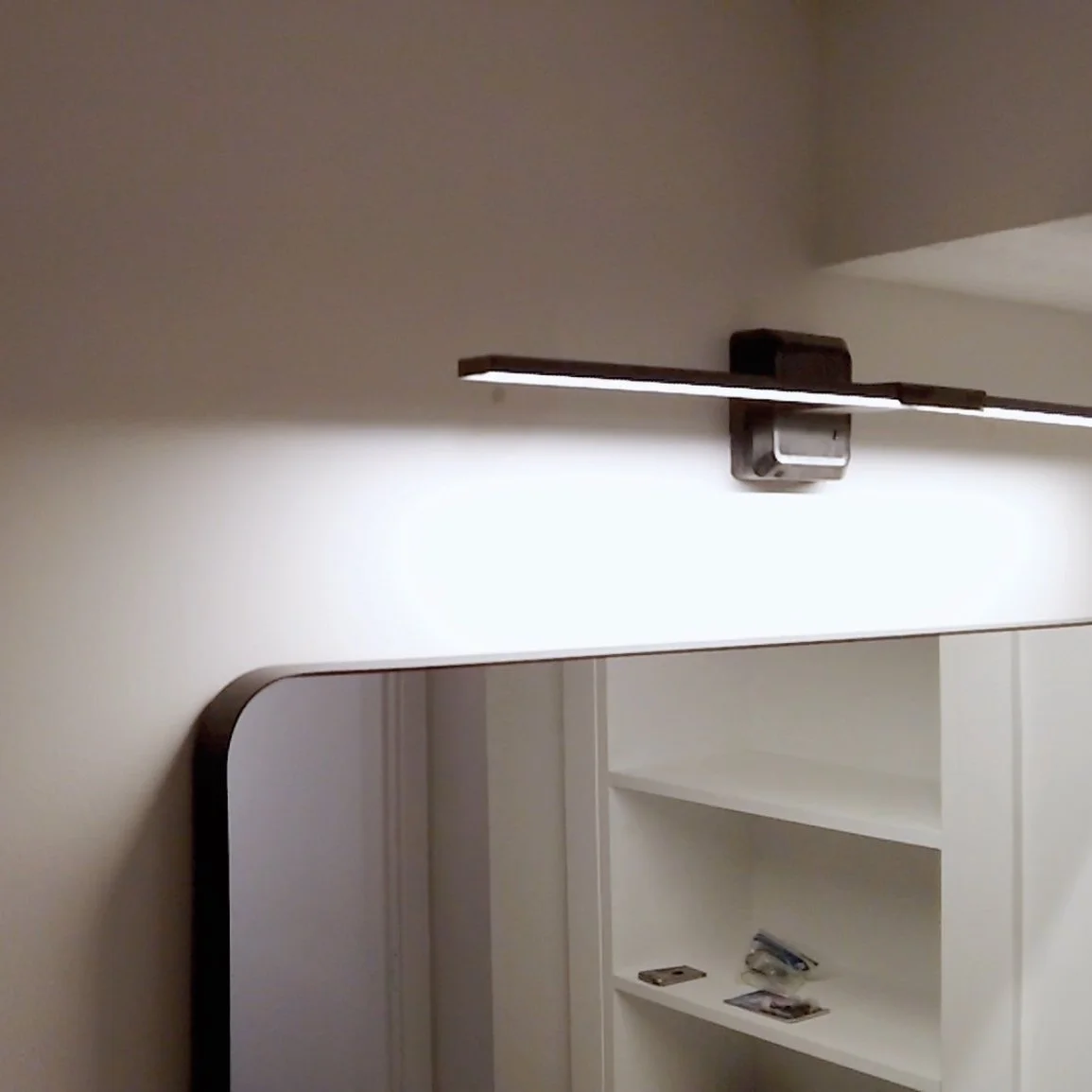 Part of a wall-mounted mirror and a modern LED light fixture with a rectangular design.