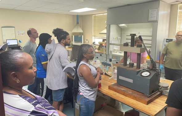  Riana Rossouw (in pink) guiding a visit to the X-Ray Fluorescence laboratory to learn about sample preparation for analysis of trace elements. 