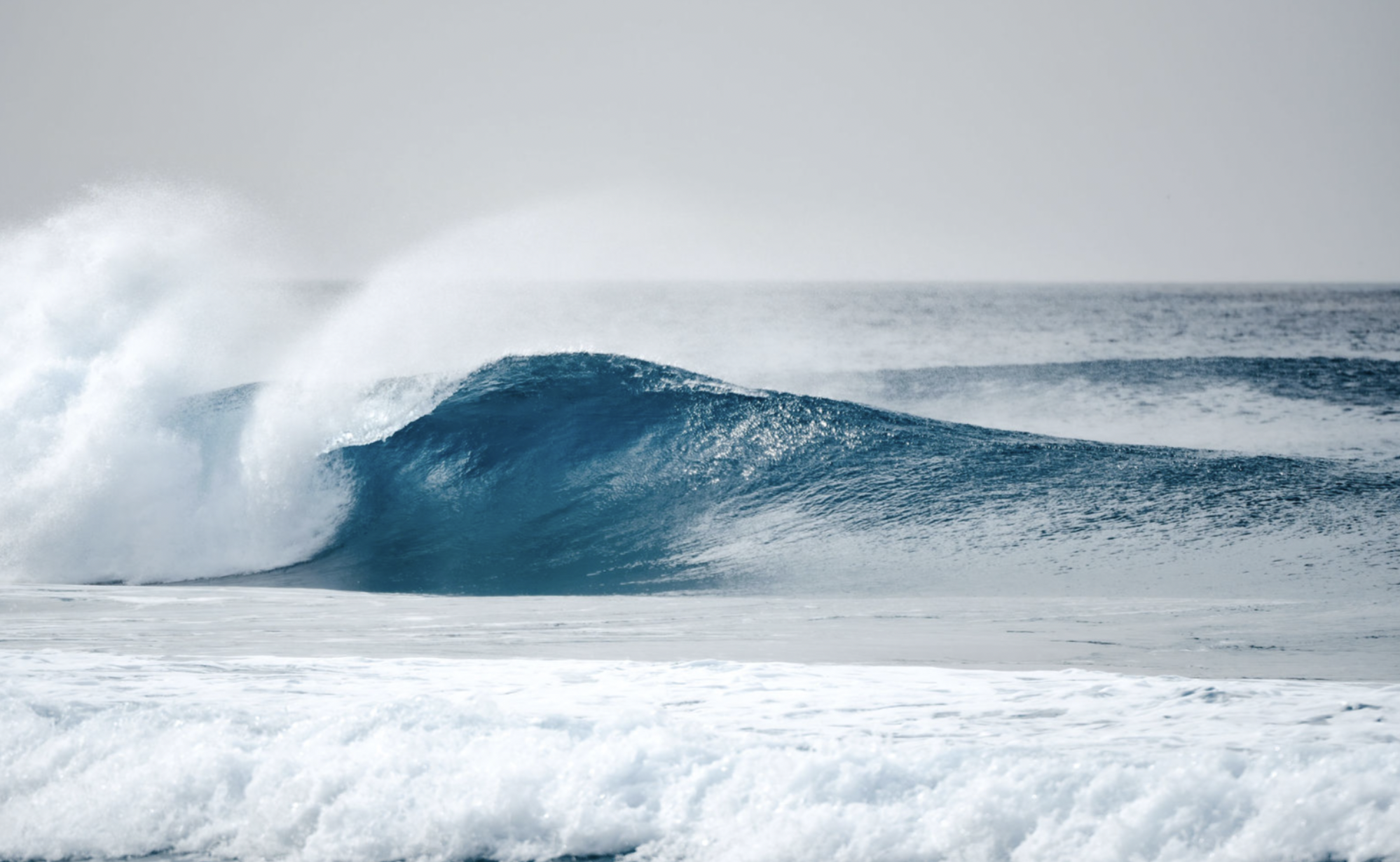 Ocean waves, with a large wave cresting and crashing.