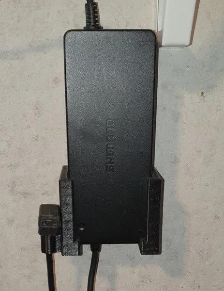 Black power supply unit mounted on a wall with cables connected.