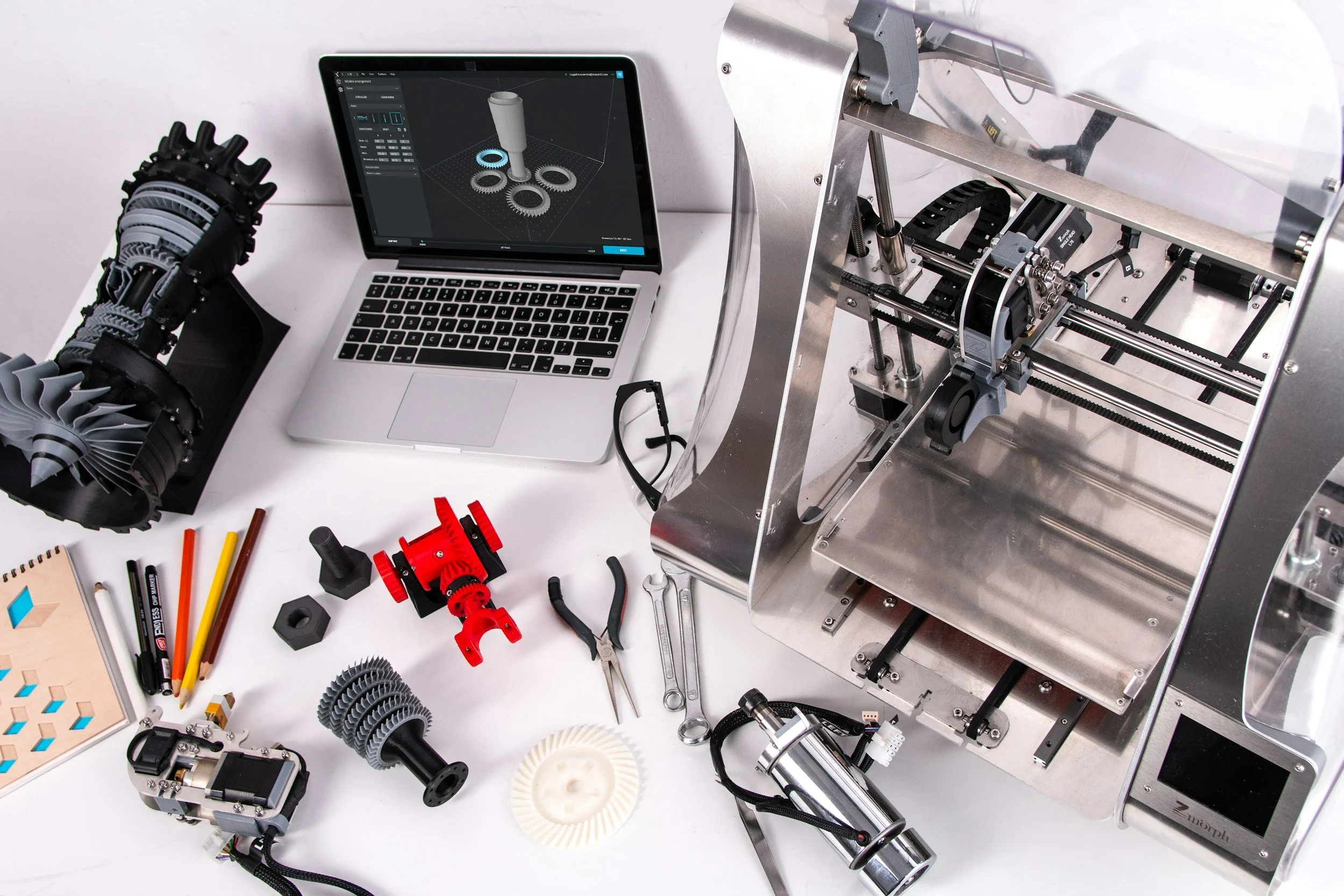 Workstation with a 3D printer, mechanical gears, tools, and design sketches, indicating a robotics or engineering project in progress.
