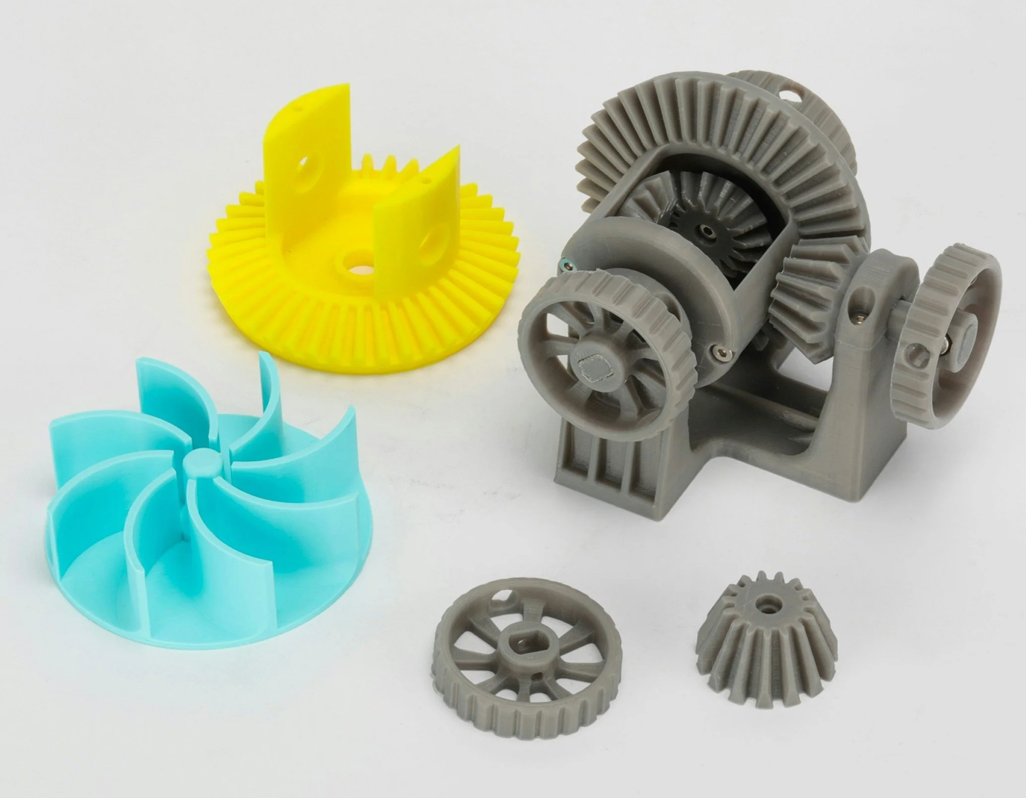 Colorful plastic gears and parts, including yellow, blue, and gray components, arranged on a white background.