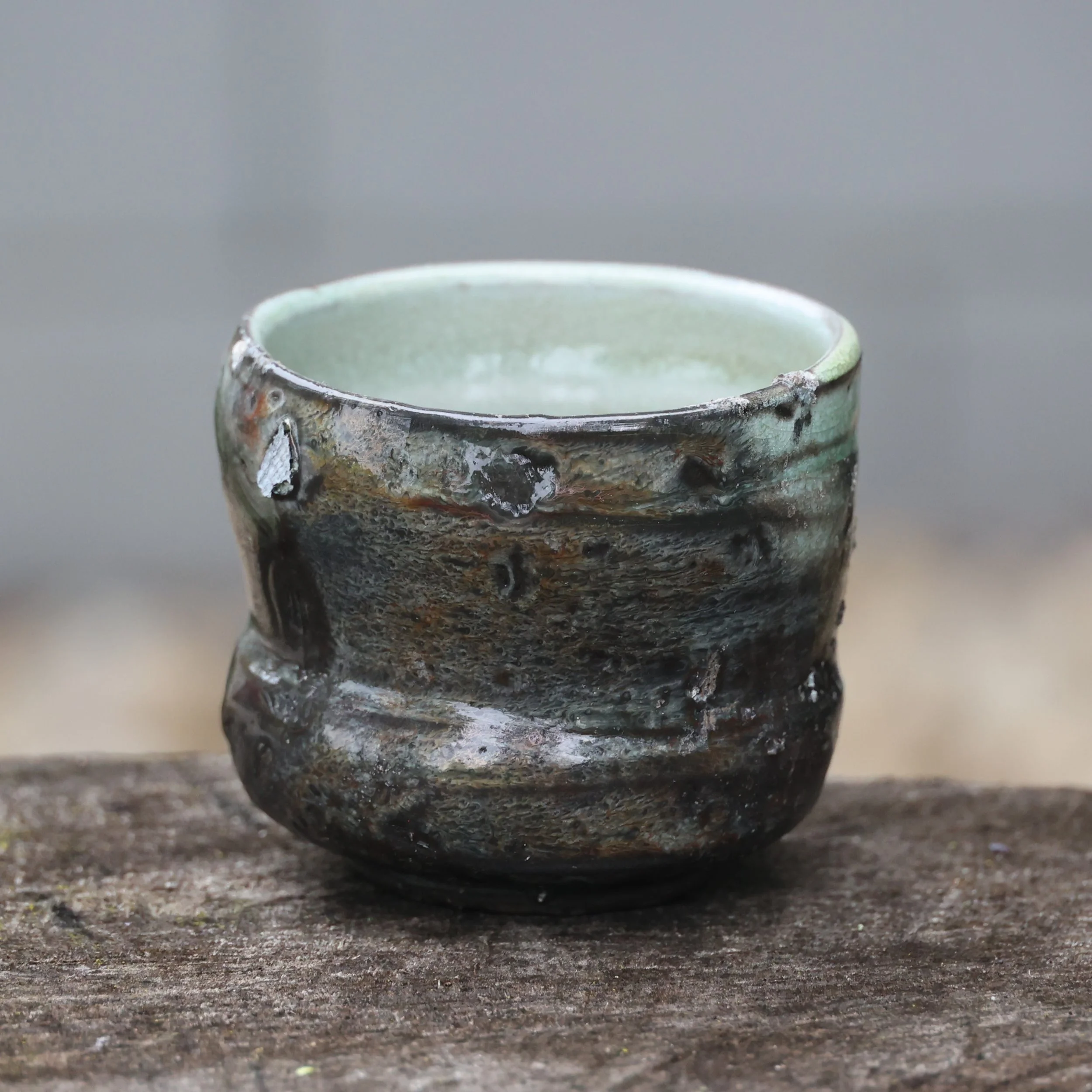 Hiki dashi tea bowl from David Smith's kiln at cone 10 or 11. Mystery glaze (but something high-iron, Celedon-esque). Pulled off the front shelf and placed in the coal bed of the firebox for about an hour (dark side was down). Then removed while red 