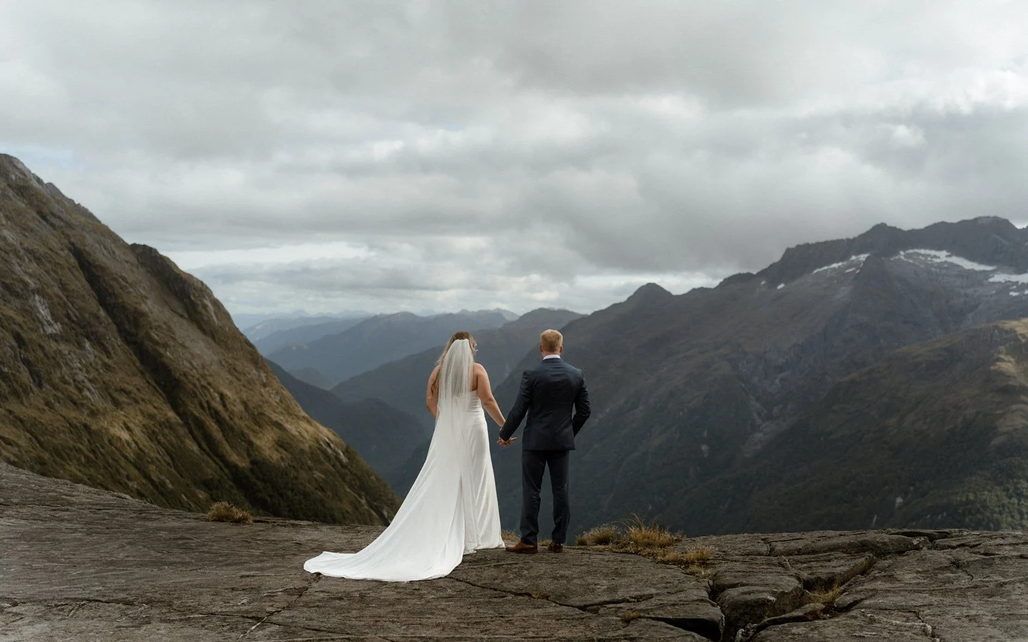 Bride and groom looking out towards Milford Sound at Lake Erskine on their wedding day. Wedding photographer Ricky B Good Photography capture the elopement perfectly.