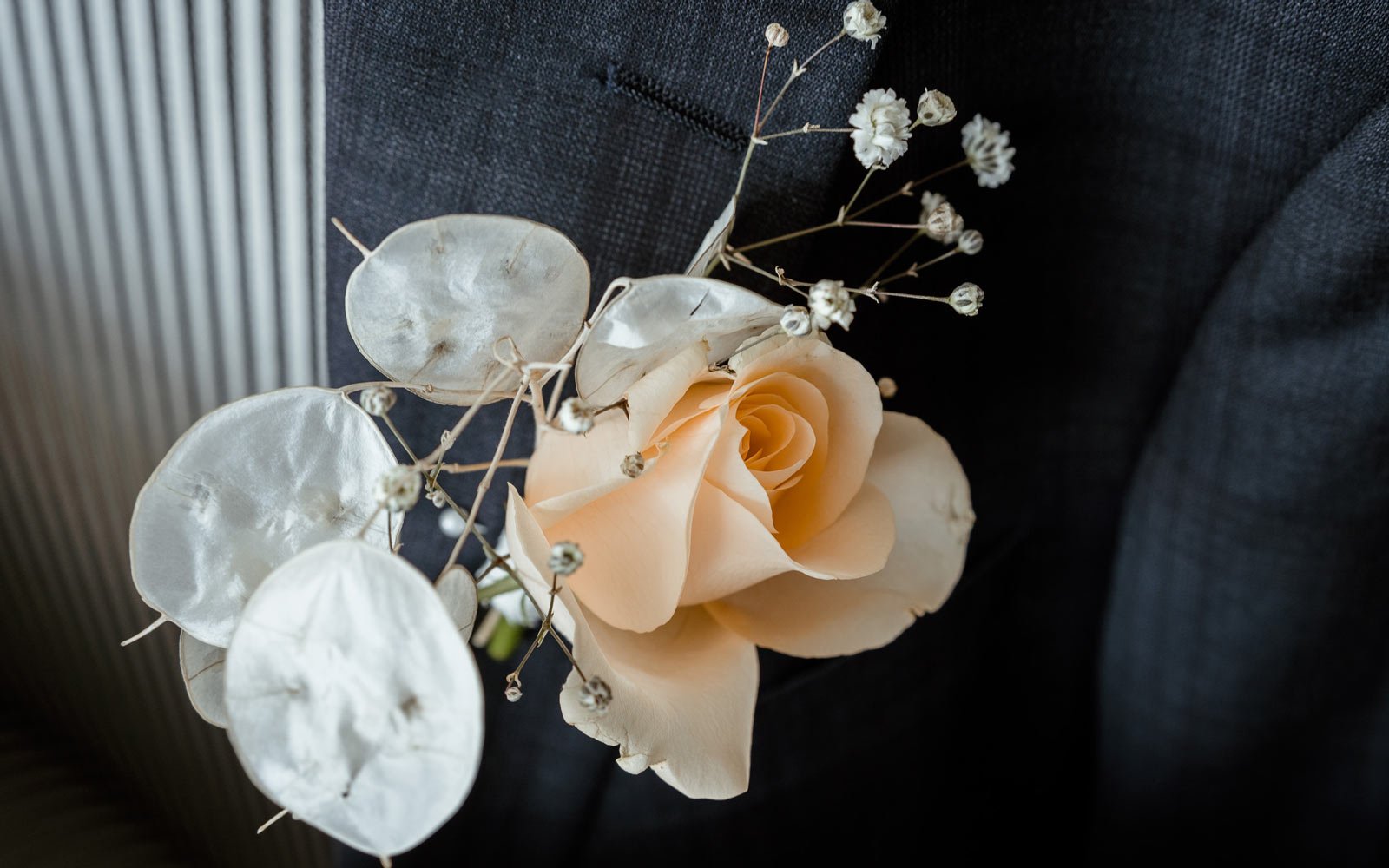 close photo of grooms orange floral buttonhole