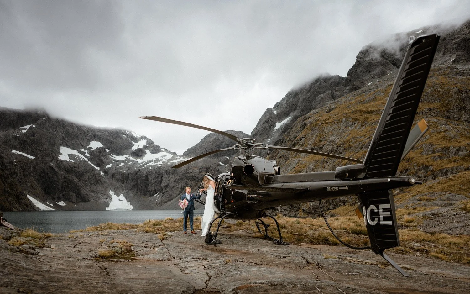 Heli wedding couple getting out of the Heliworks helicopter at Lake Erskine for their elopement in Queenstown