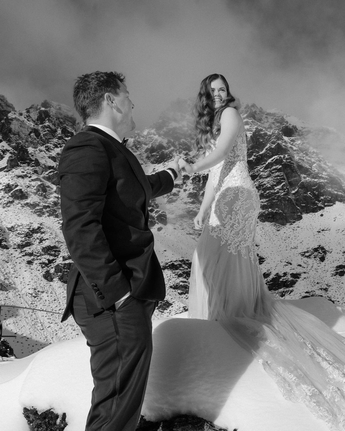 bride and groom with helicopter in the background up the remarkable mountains