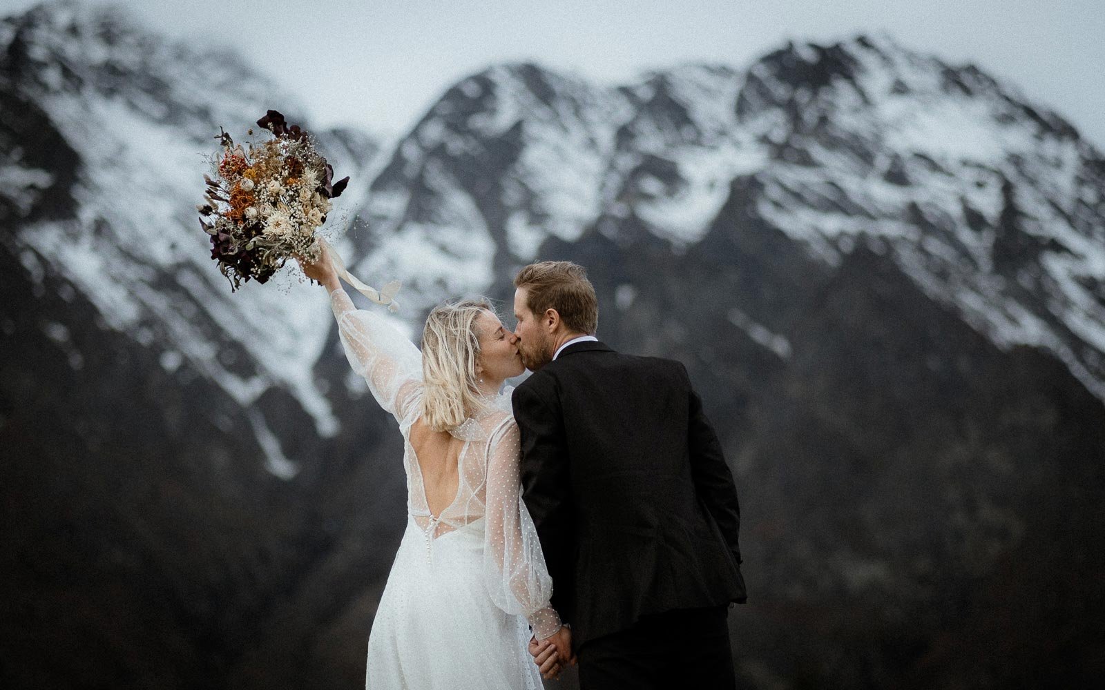 bride share their first kiss at Queenstown elopement with a dramatic view of the Remarkables in the background
