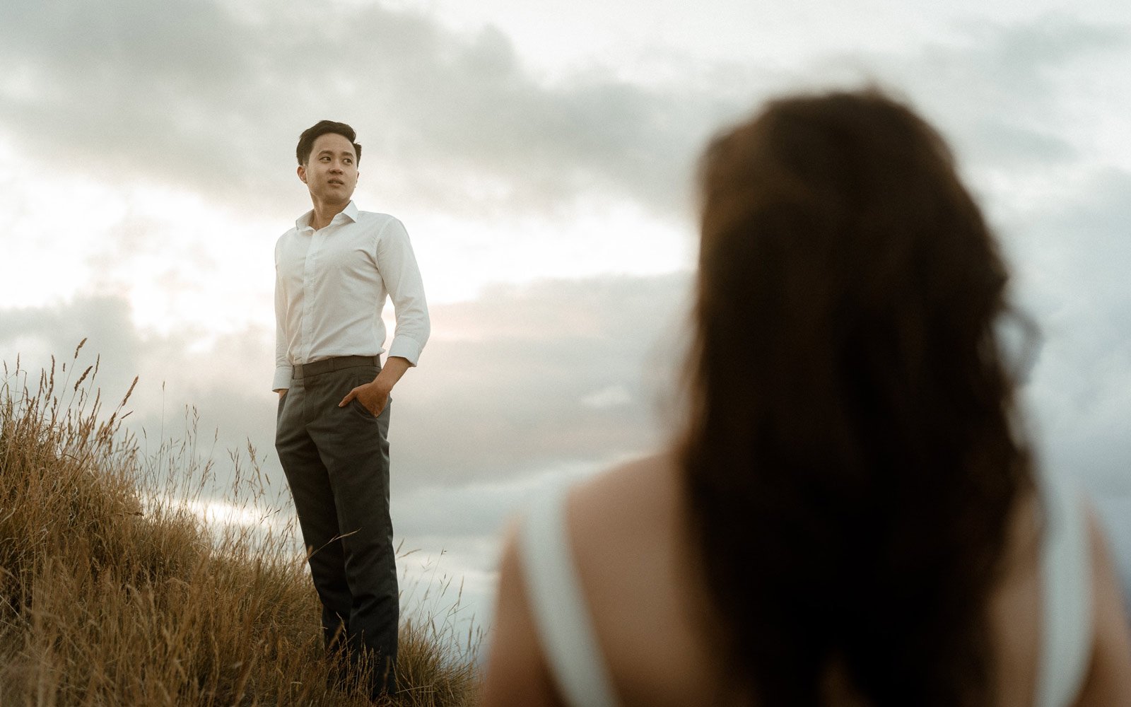 Groom standing in tussocks looking at mountains