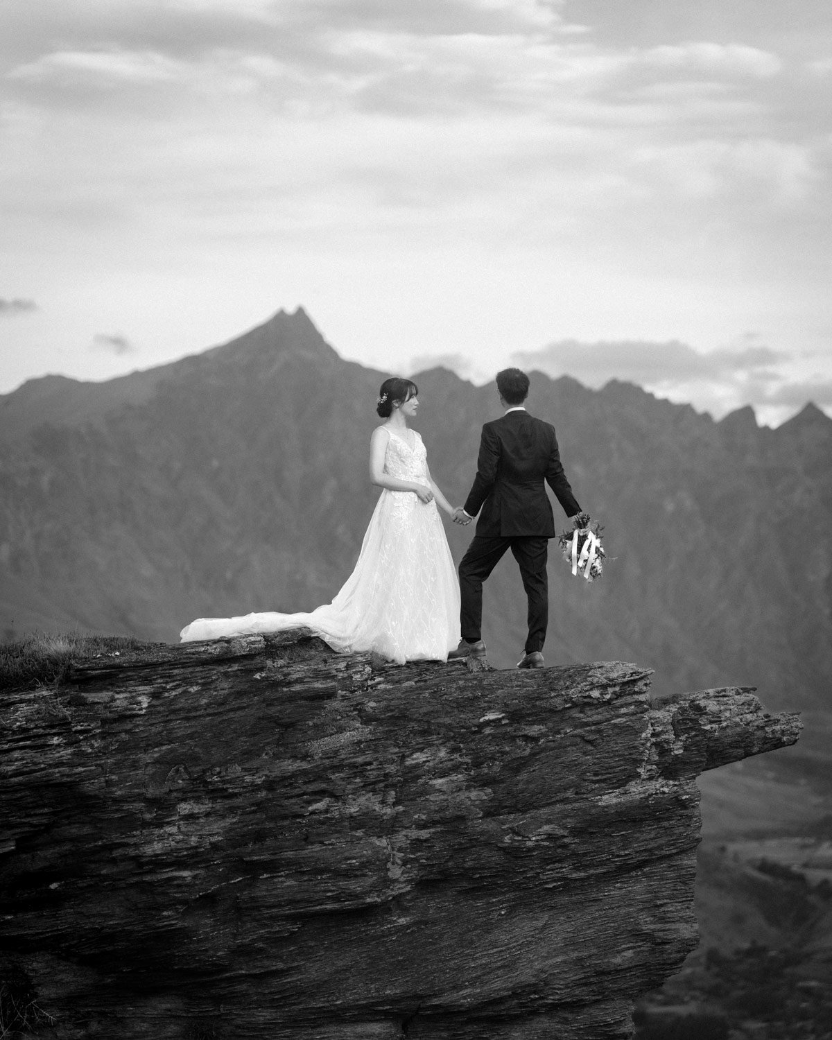 Wedding couple stand on a cliff up Coronet Peak after getting married in Queenstown with Wild Love Elopements and Ricky B Good Photography