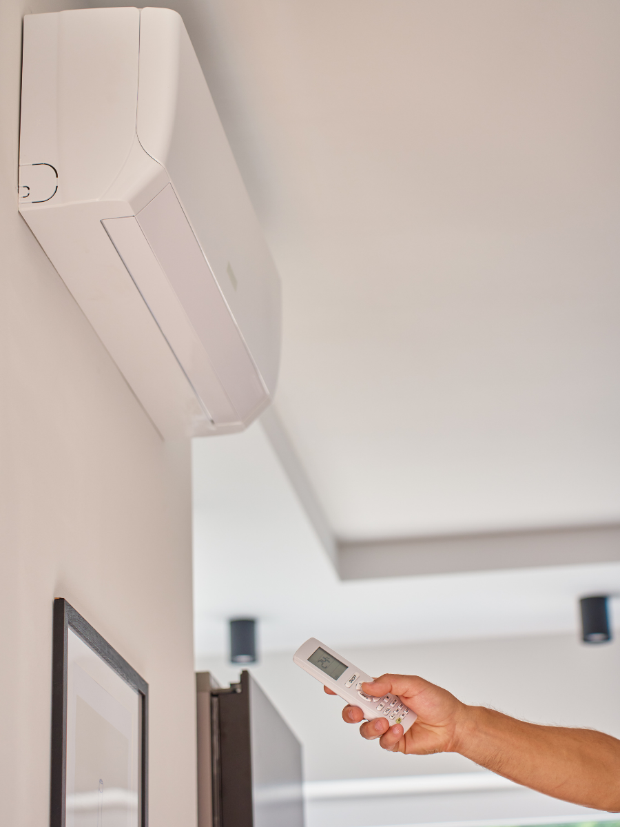 Homeowner adjusting a wall-mounted ductless mini-split with a remote control