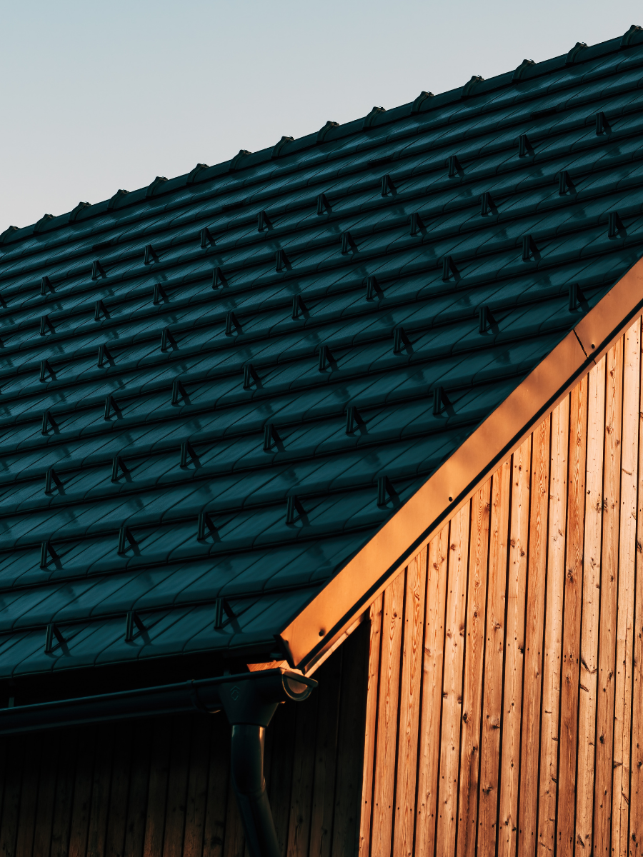 Dark metal tile roof with matching gutter and downspout