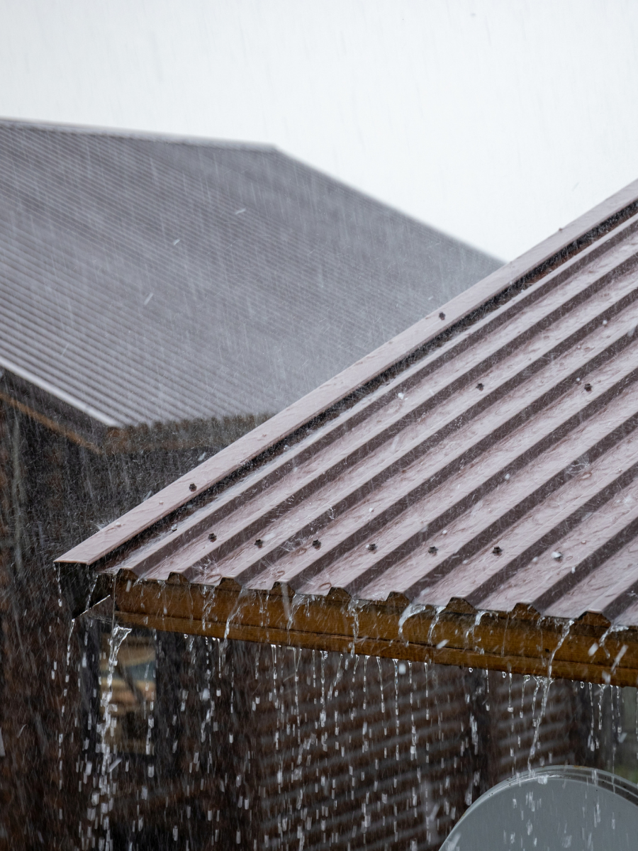 Rainwater draining from the edge of a corrugated metal roof