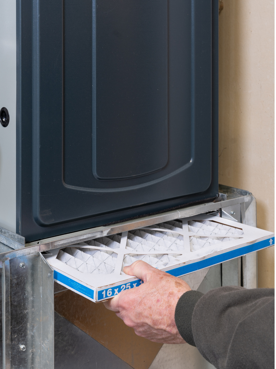 Technician installing an air filter in a residential furnace system