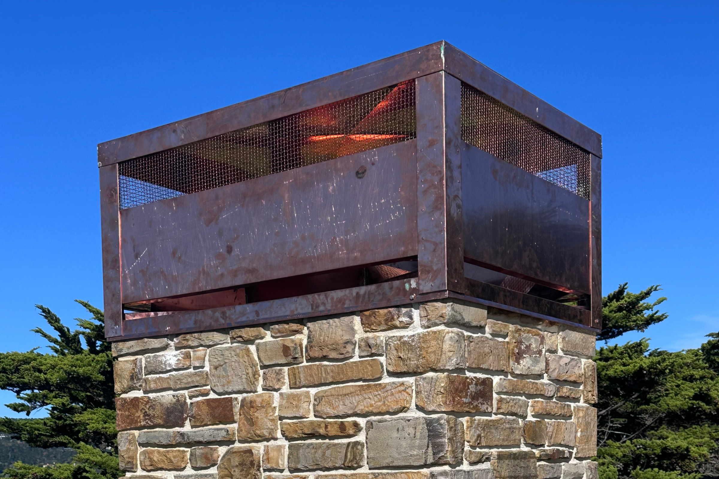 Custom fabricated copper chimney cap installed on a stone chimney as part of a high-end sheet metal project in Carmel, CA