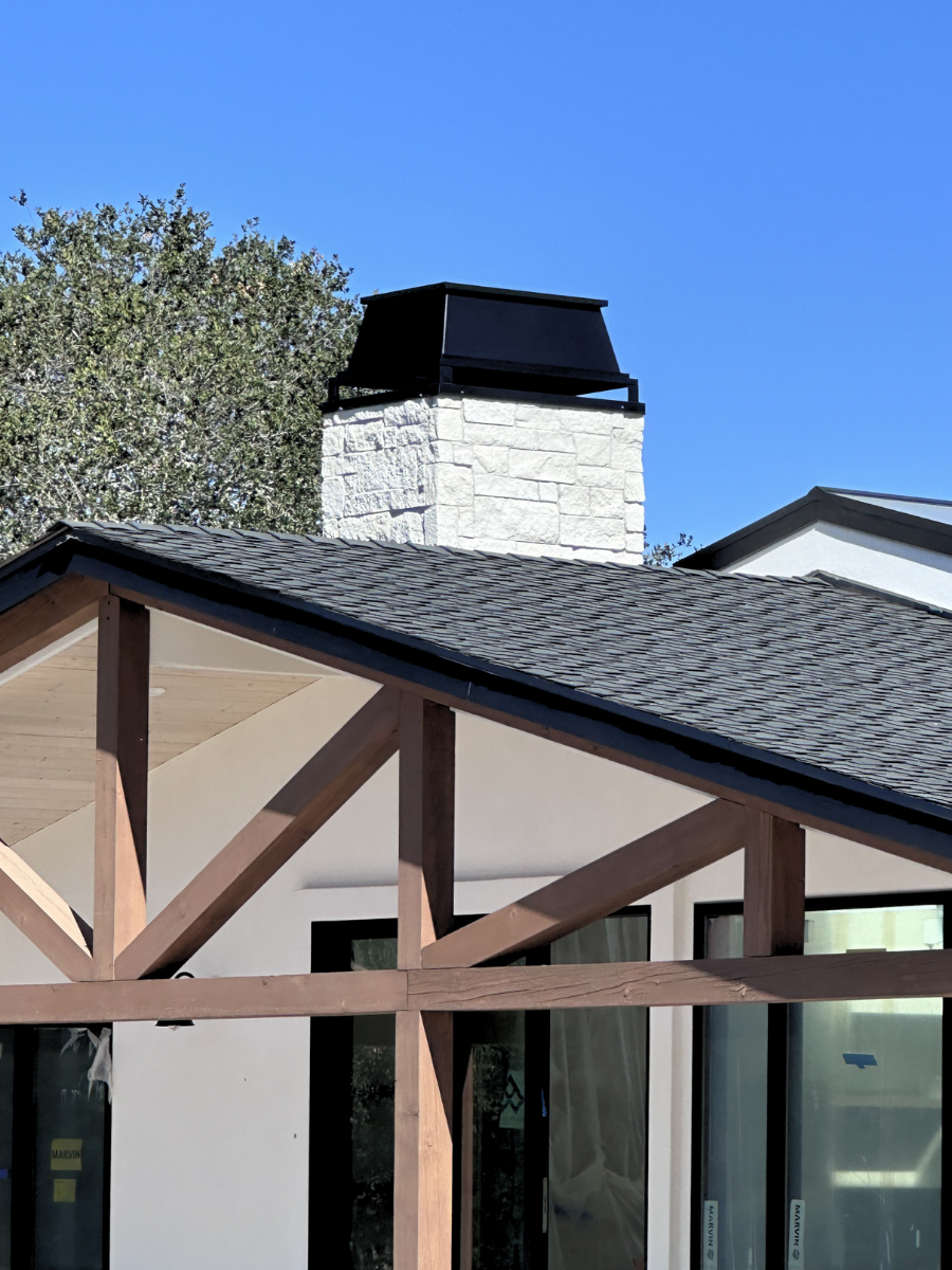 Custom black metal chimney cap installed on a stone chimney
