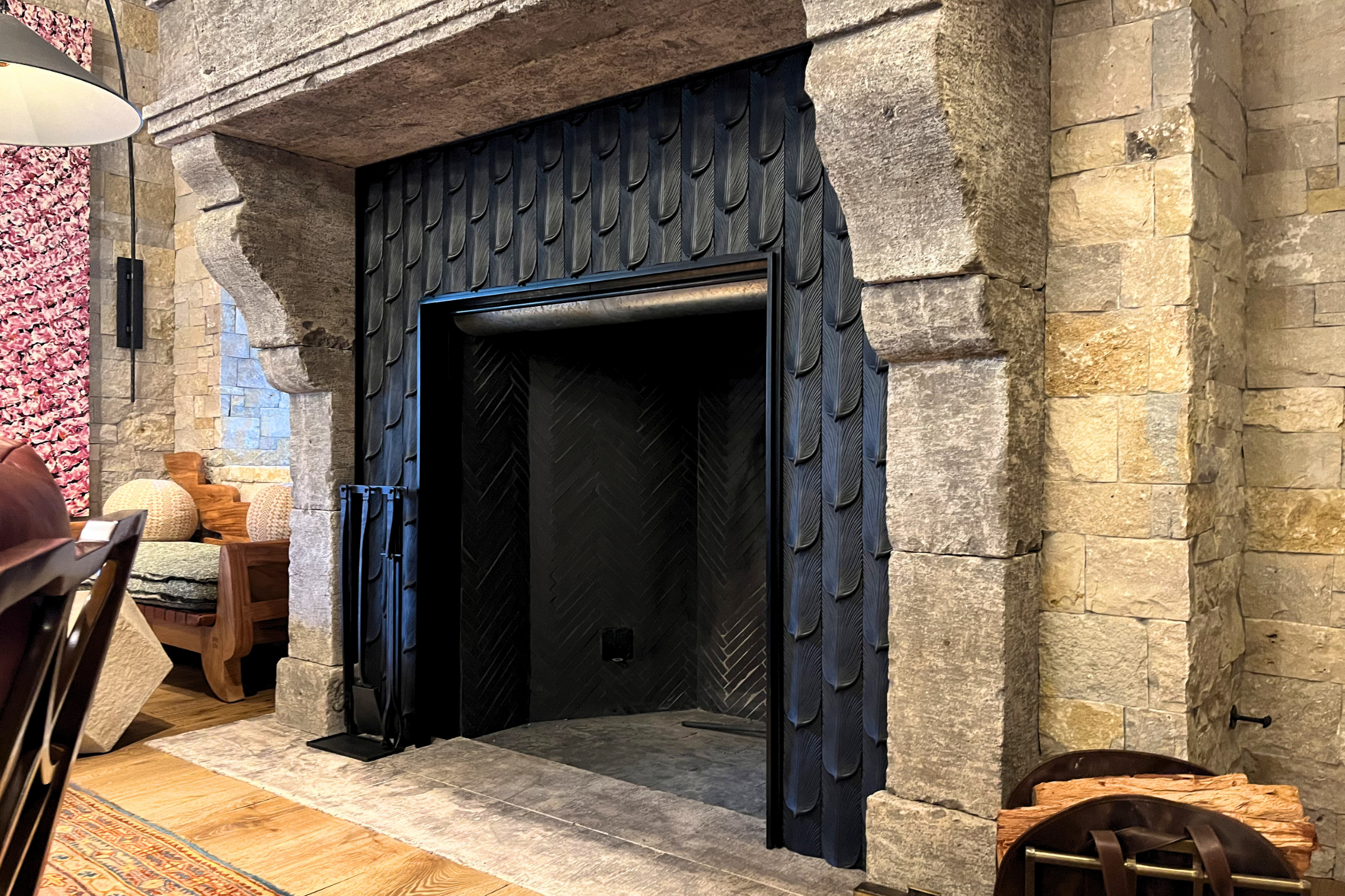 Custom fabricated sheet metal fireplace surround installed within a natural stone fireplace in Carmel Valley California